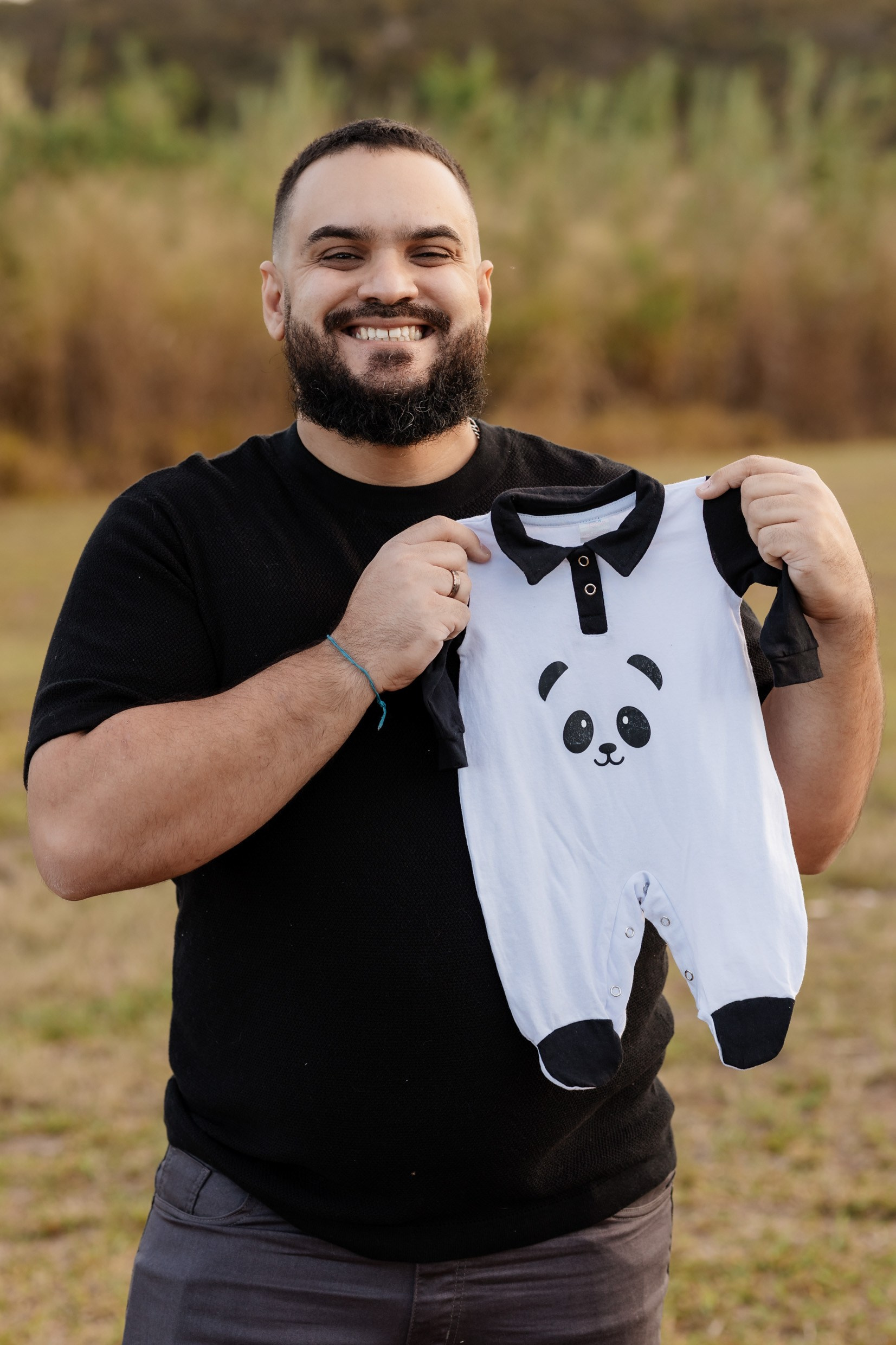 Pai segurando roupinha do bebê em ensaio gestante