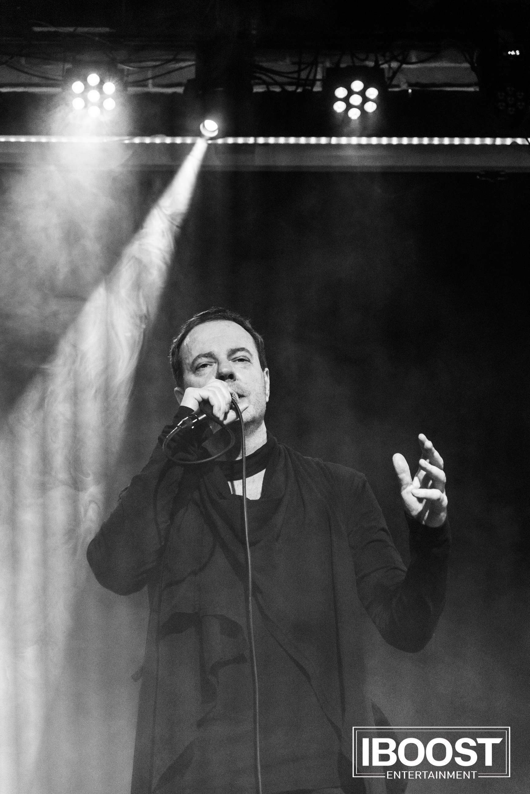 Black-and-white portrait of the lead vocalist of Animal JazZ singing into a microphone under a beam of light.