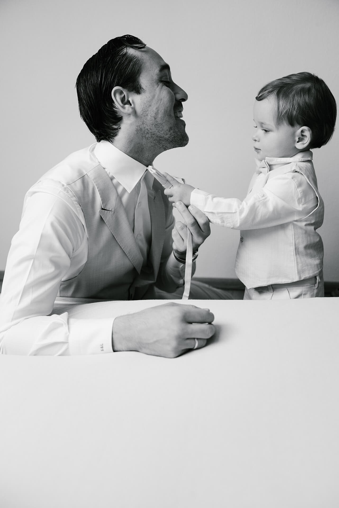 Groom adjusting tie with child at Villa Monastero