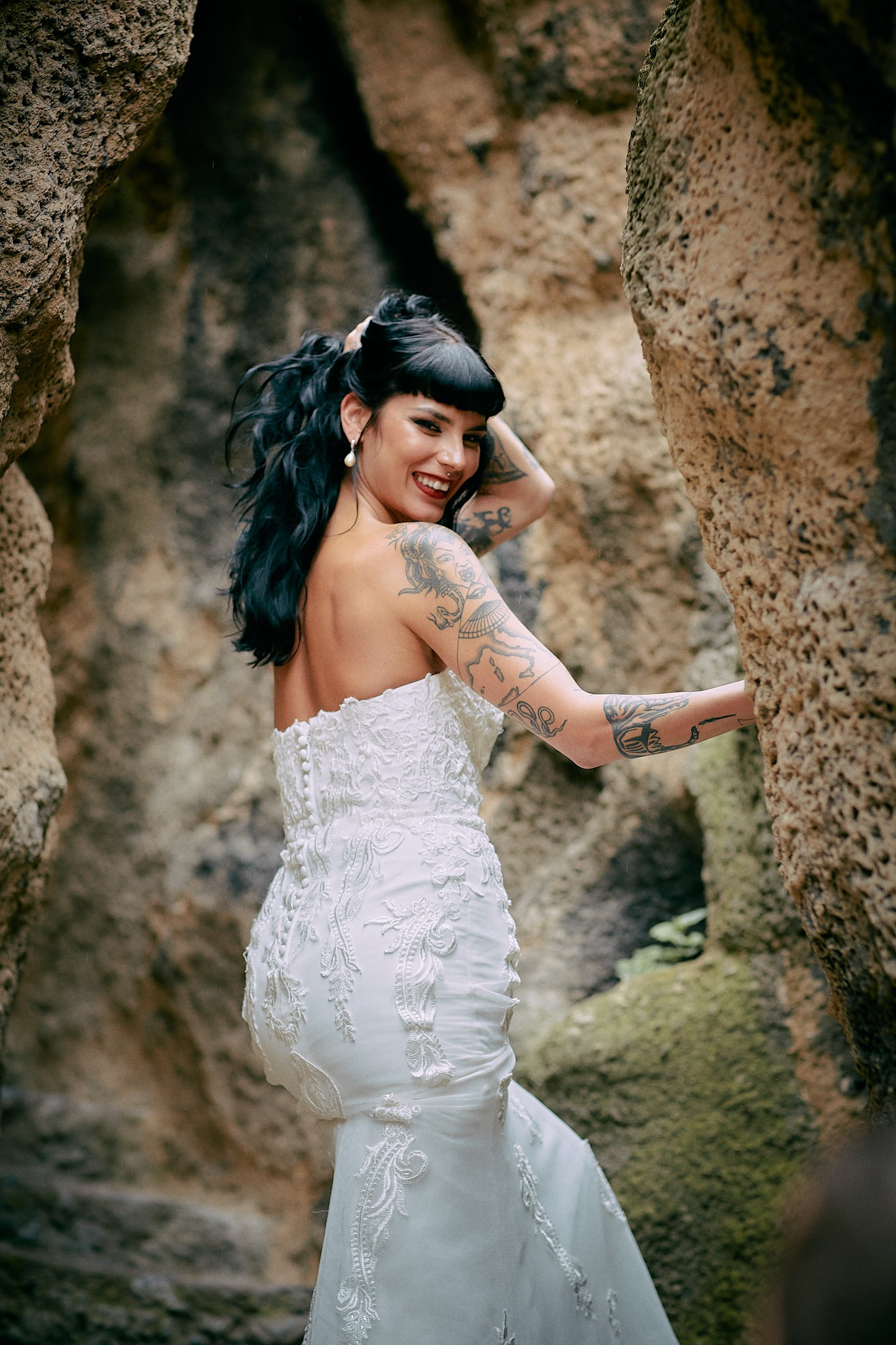 Tattooed bride sensual pose in dramatic Grebovka rock grotto.