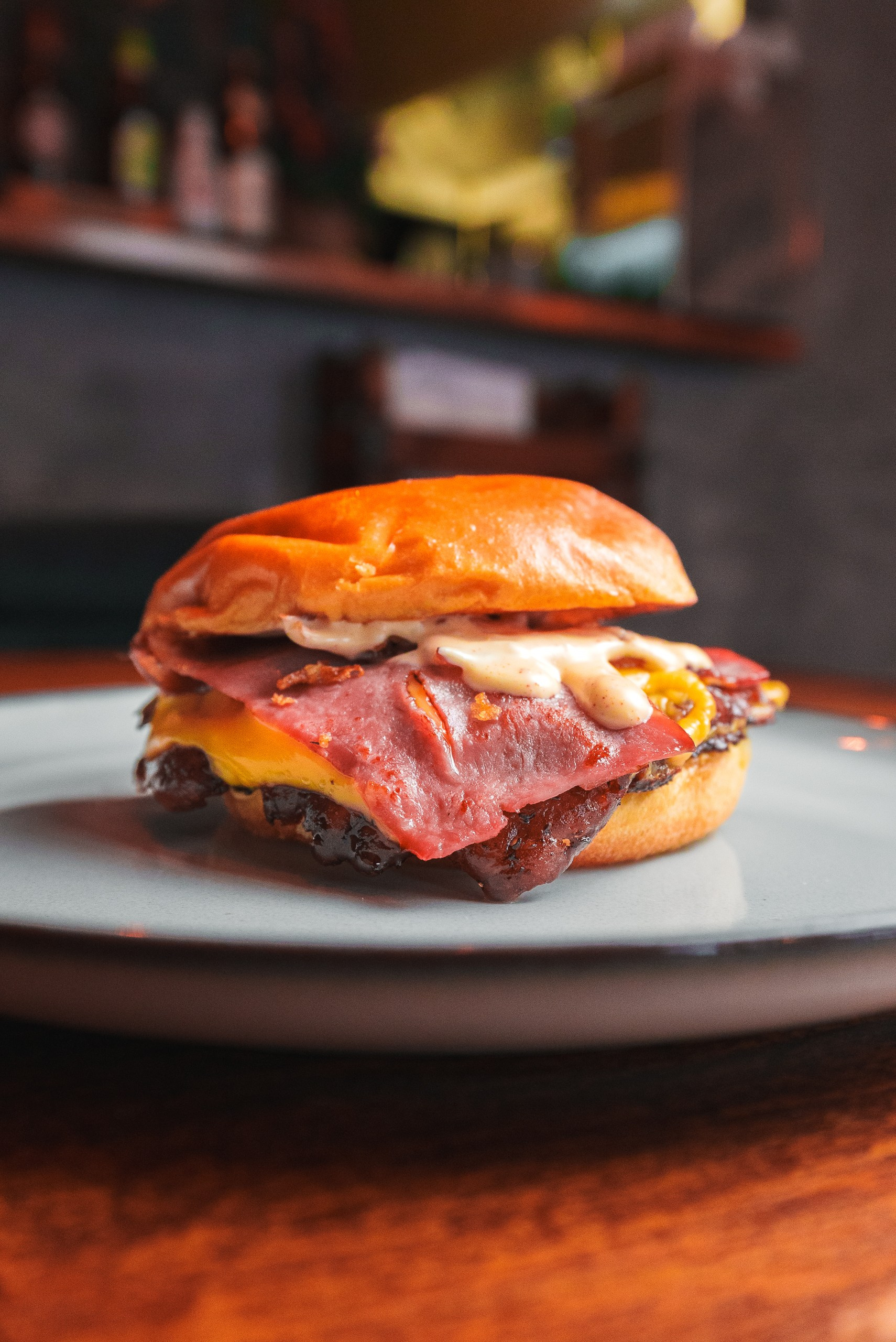 Fotografia gastronómica e de produto de um hambúrguer artesanal com bacon e queijo num prato, produzida pela Khave Media