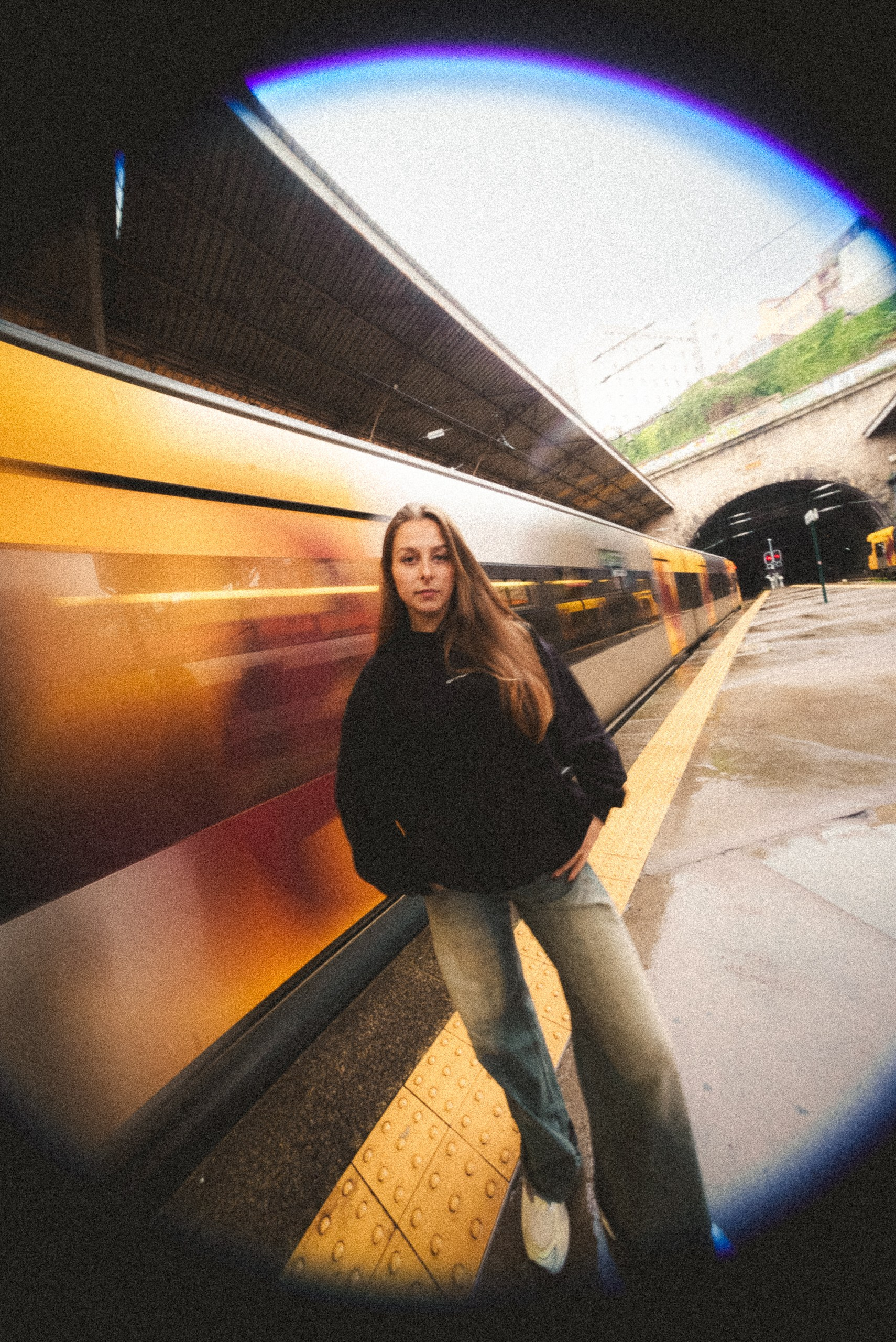 Fotografia de moda e urbana em olho de peixe com uma jovem numa plataforma de estação com comboio em movimento, captada pela Khave Media