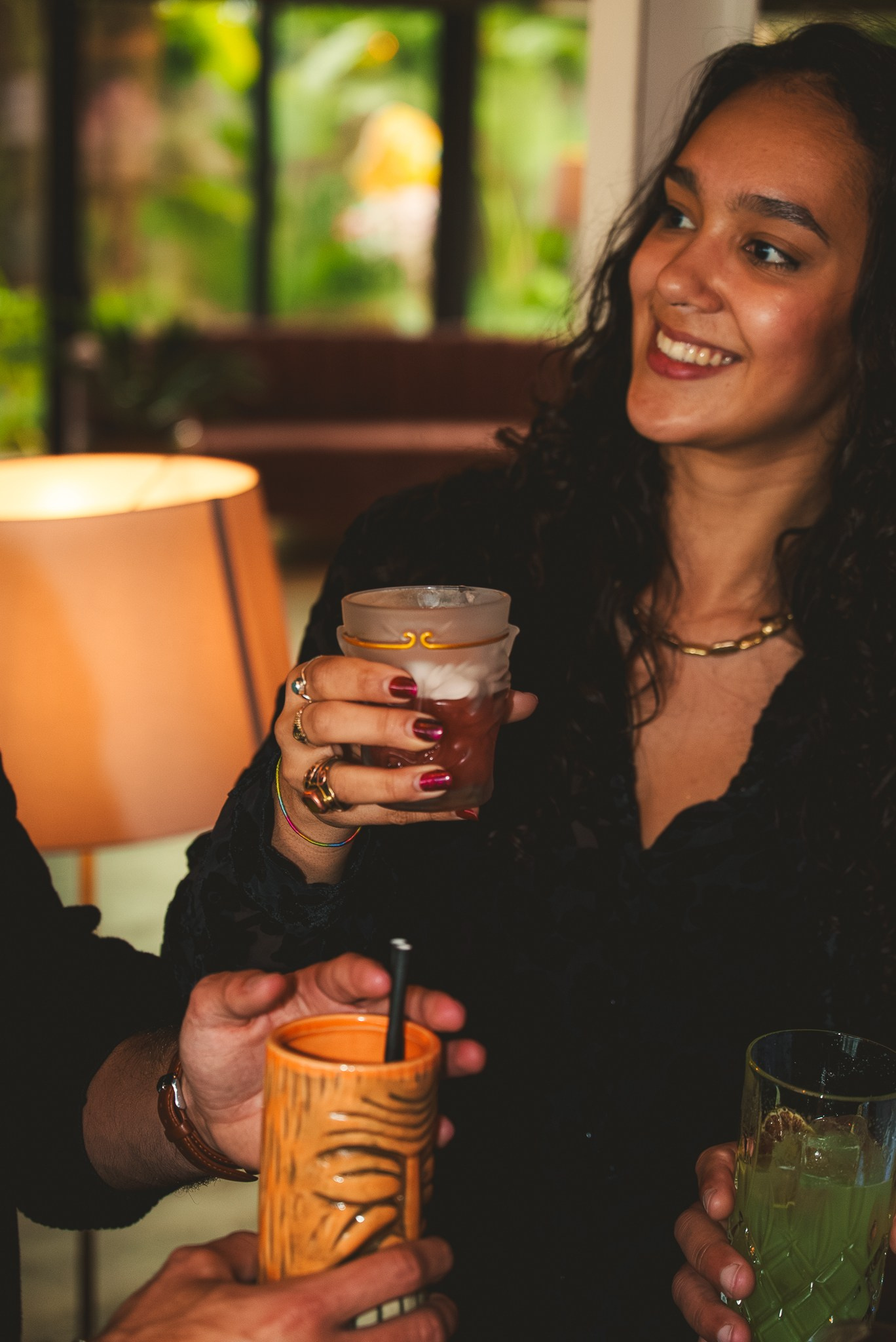 Fotografia de lifestyle de uma mulher a sorrir e a brindar com cocktails num bar moderno, produzida pela Khave Media