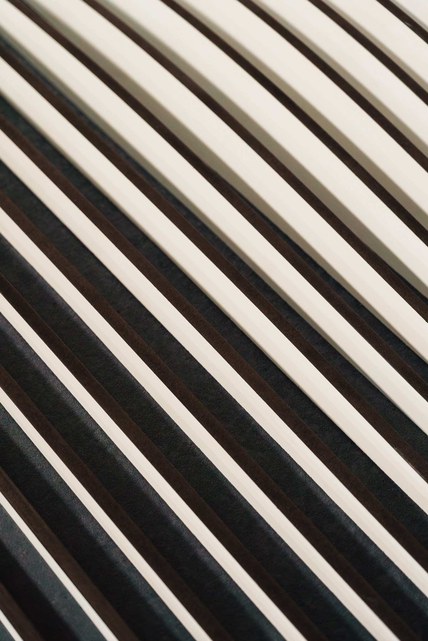 Fotografia de detalhe e textura de painéis acústicos e decorativos diagonais com iluminação contrastante, captada pela Khave Media