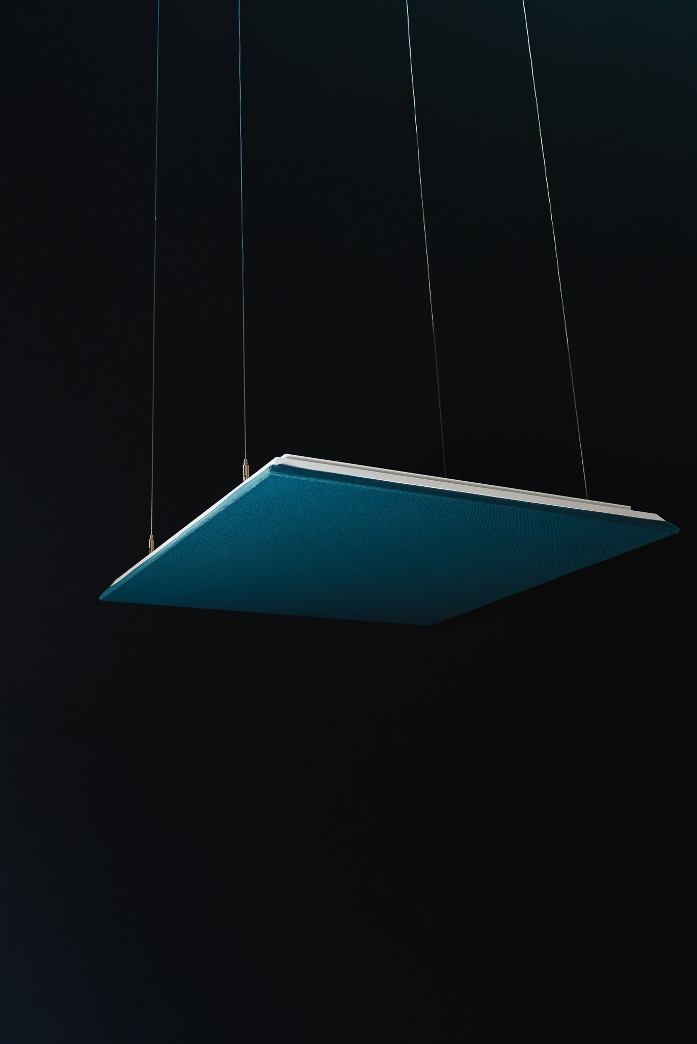 Fotografia de design e arquitetura minimalista de um painel acústico azul suspenso contra um fundo escuro, produzida pela Khave Media