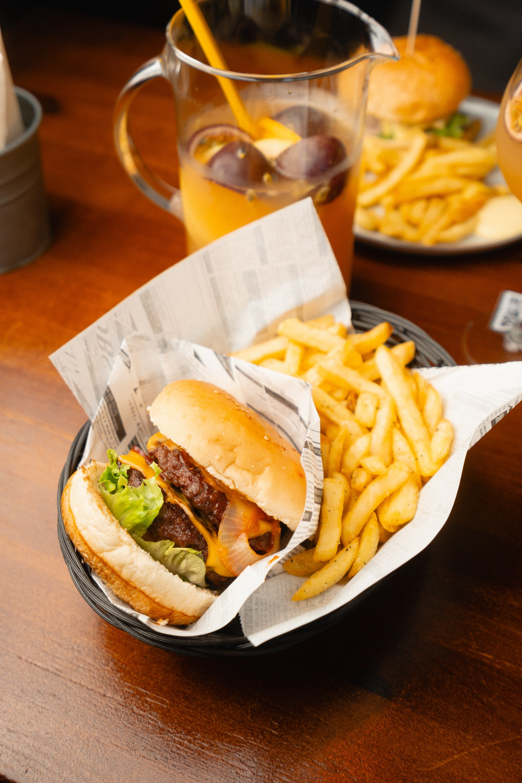 Fotografia de restauração destacando um hambúrguer artesanal servido com batatas fritas e bebida numa mesa, produzida pela Khave Media