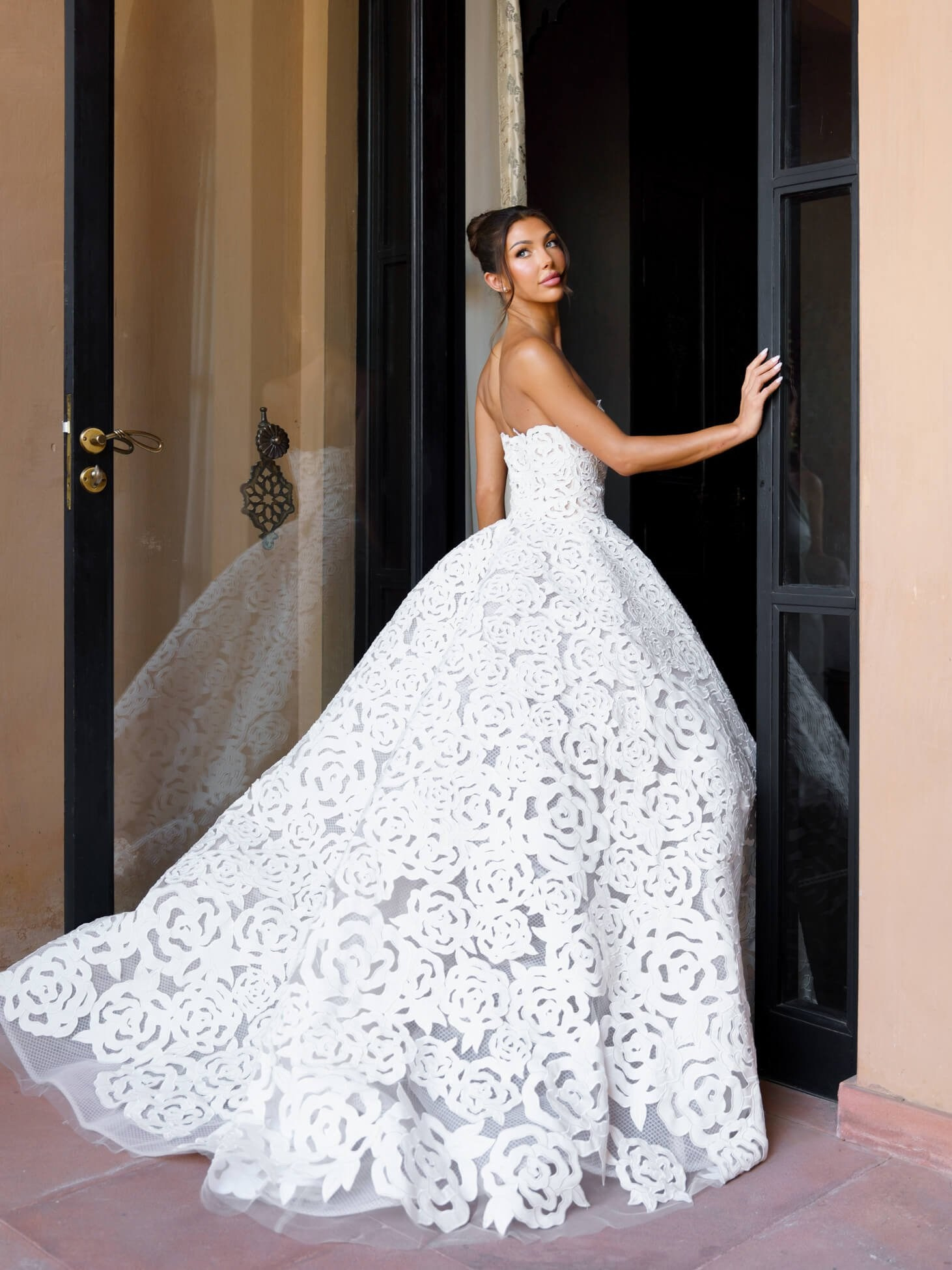 Bride in lace ball gown standing in villa doorway