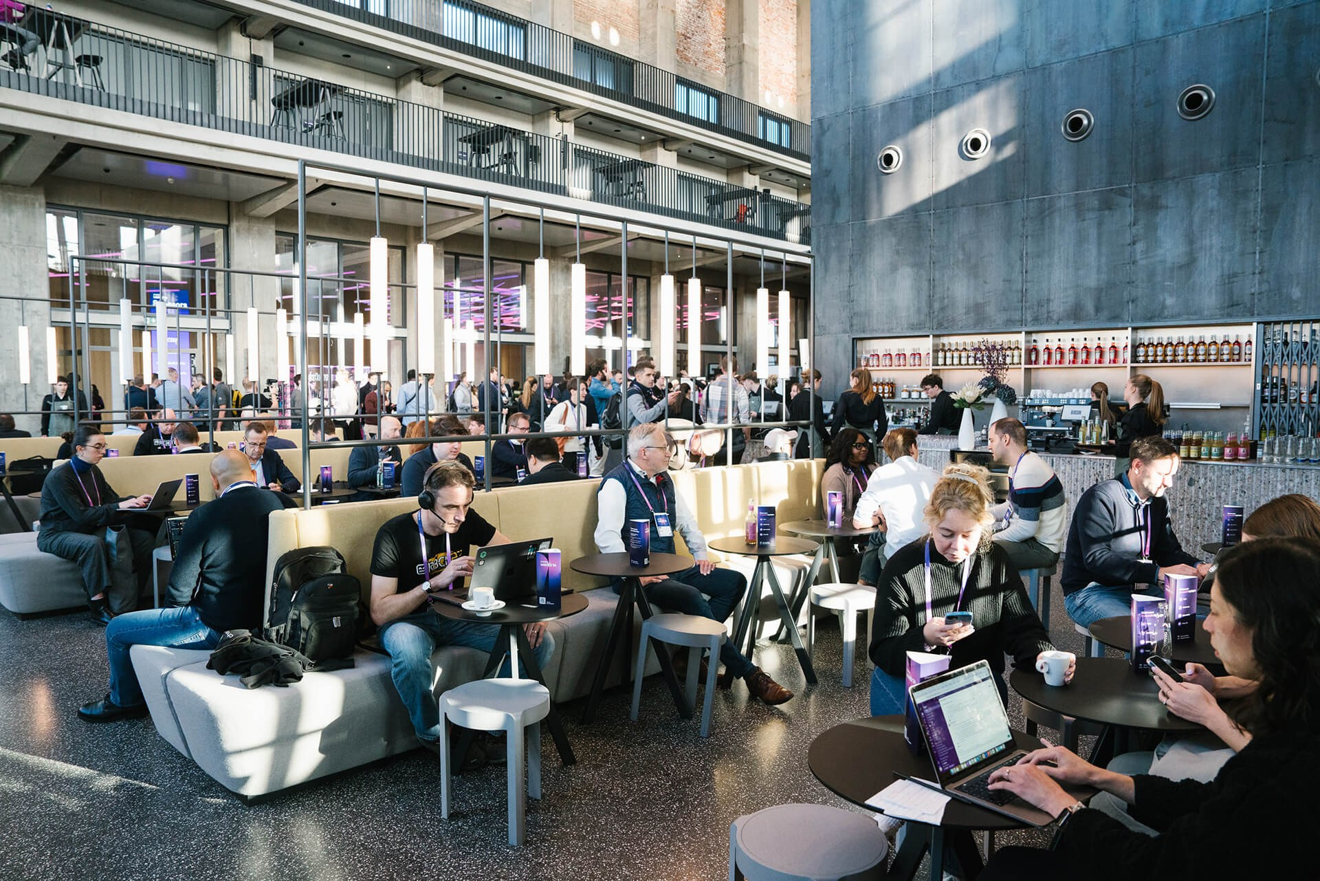 Konferenzteilnehmer arbeiten an Laptops in einer großen Networking-Lounge in München
