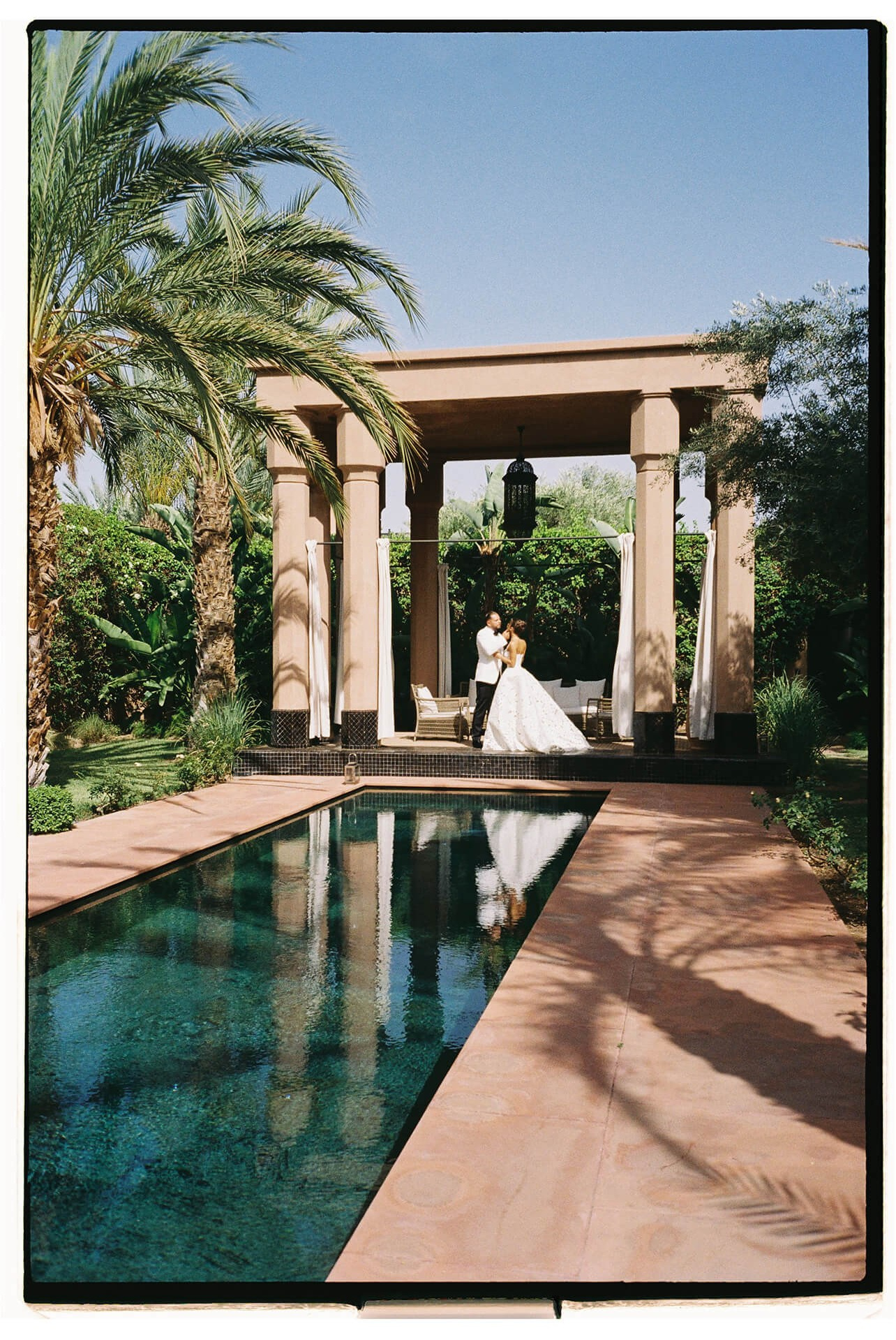 Bride in a white dress beside a long pool, destination wedding in Marrakesh, Morocco