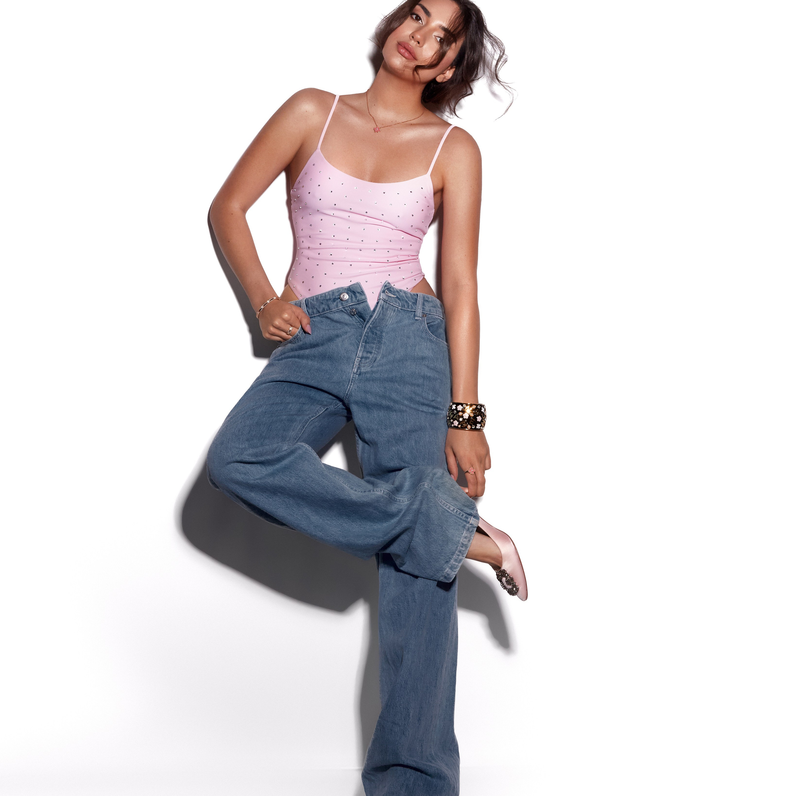 Fashion фотограф Ханна Асаулова | Стильна модель у рожевому топі та широких джинсах у невимушеній позі на білому фоні, fashion-фотосесія у Вільнюсі.