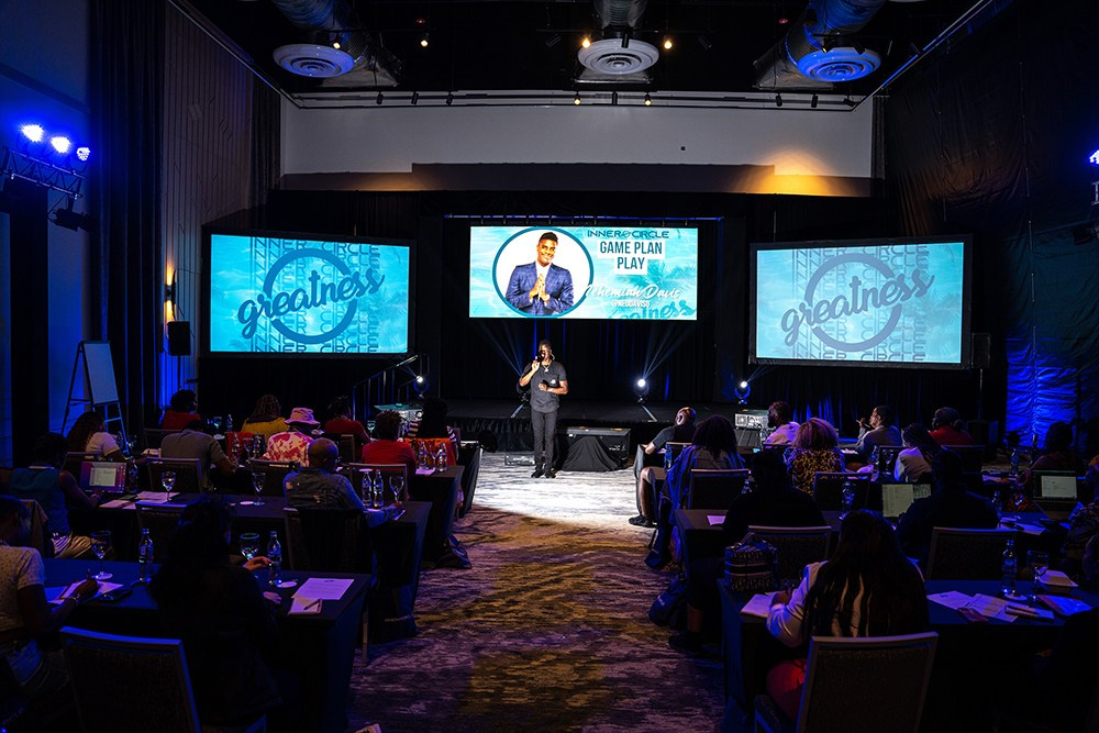 Speaker delivering a corporate presentation on stage to an attentive audience.