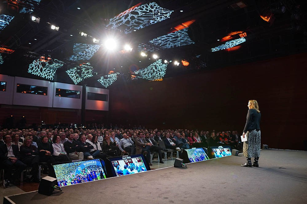 A wide-angle view of a speaker on stage addressing the audience during a corporate sales kick-off event at the Hilton in Prague.