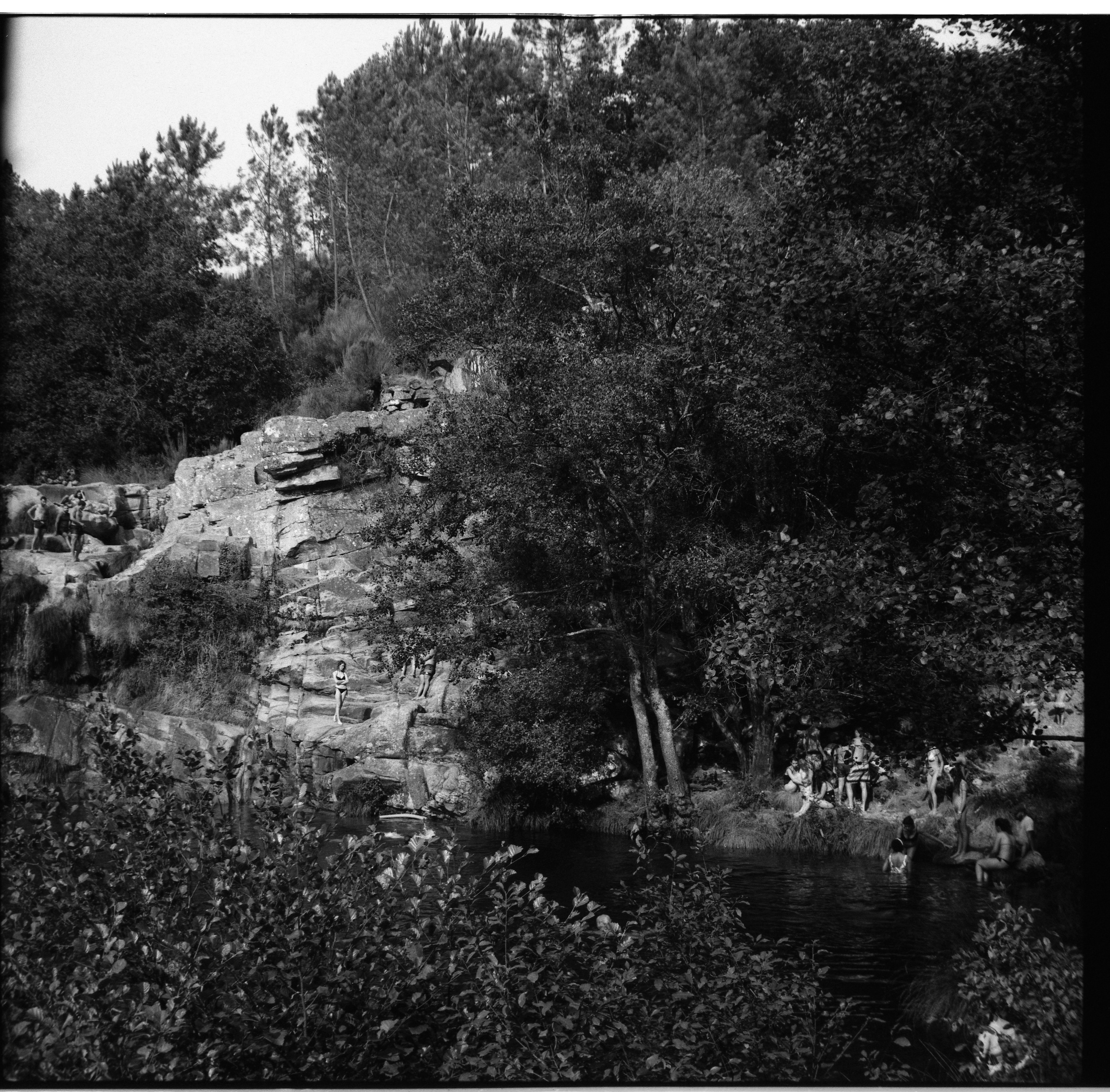 Documentary fine art photography, Summer in Portugal. Locals, old people, boys, girls, men and women with babies enjoying the coolness of a waterfall in the woods