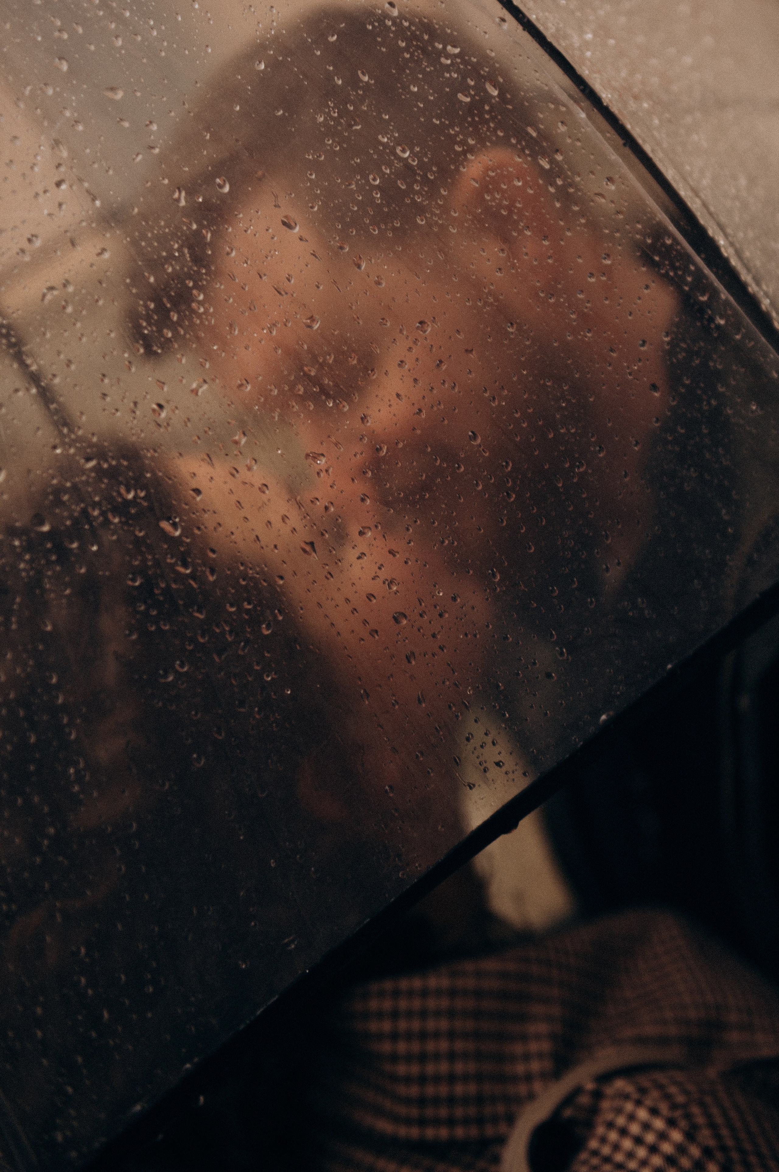 Bride and groom kissing under an umbrella on a rainy wedding day in Italy. Wedding Photographer in Milan