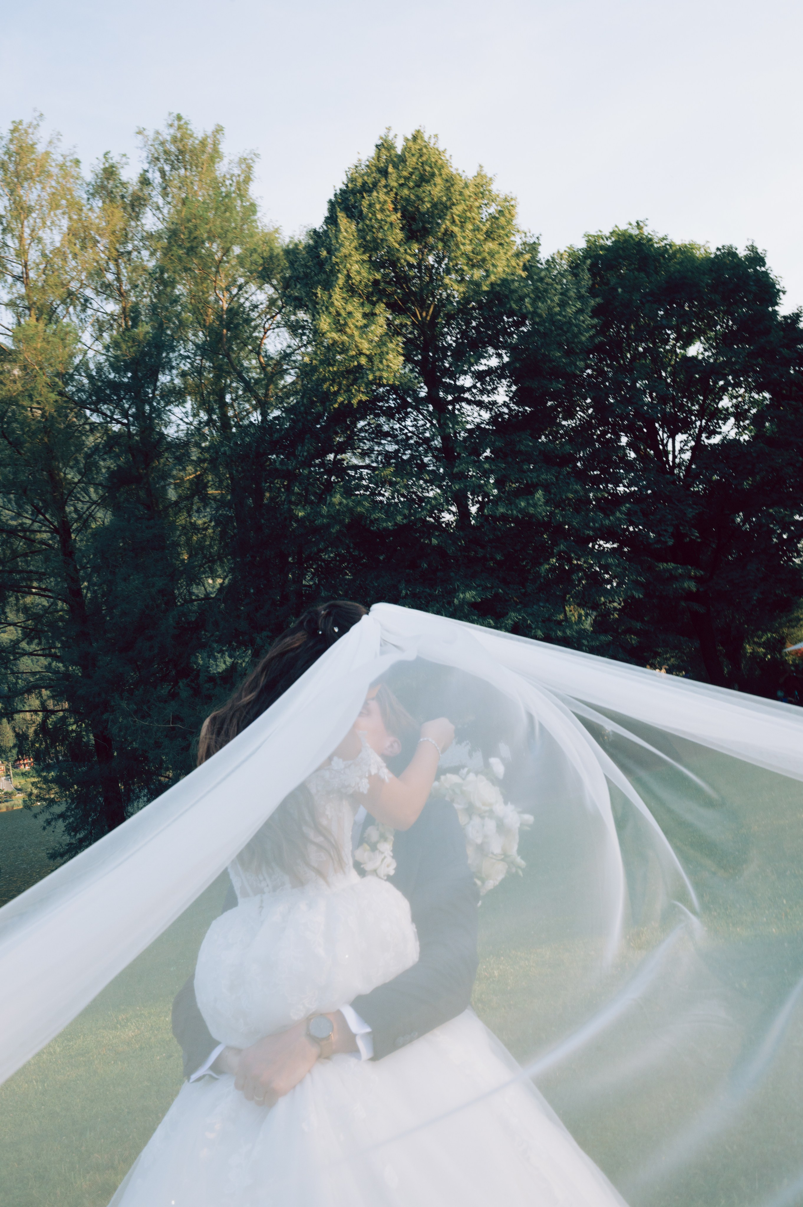 Romantic bride and groom portrait beneath a flowing wedding veil in an Italian garden. Lake Como Destination wedding photographer