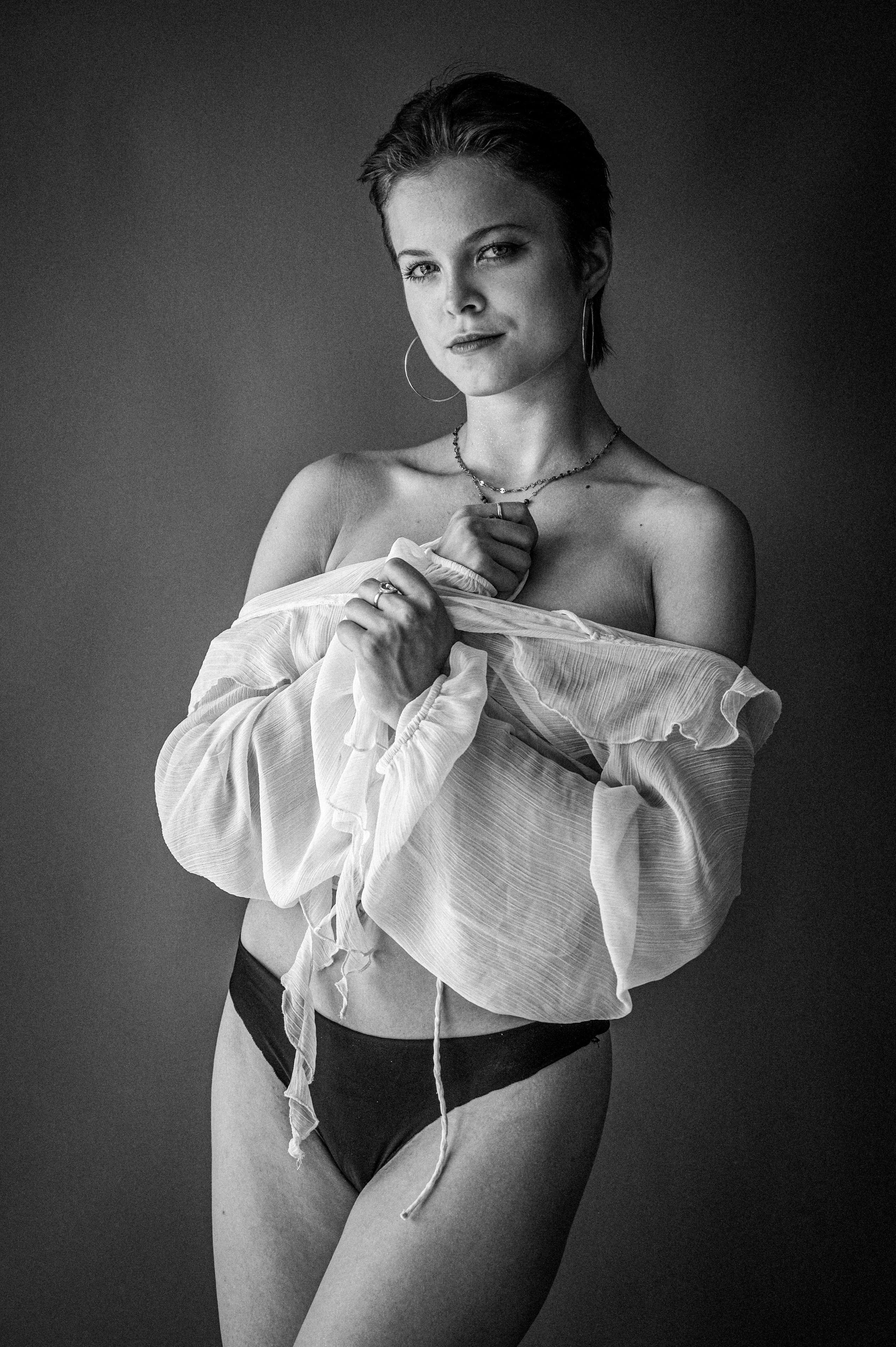 Modelka Marta w białej, lekkiej tkaninie na ciemnoszarym tle studyjnym