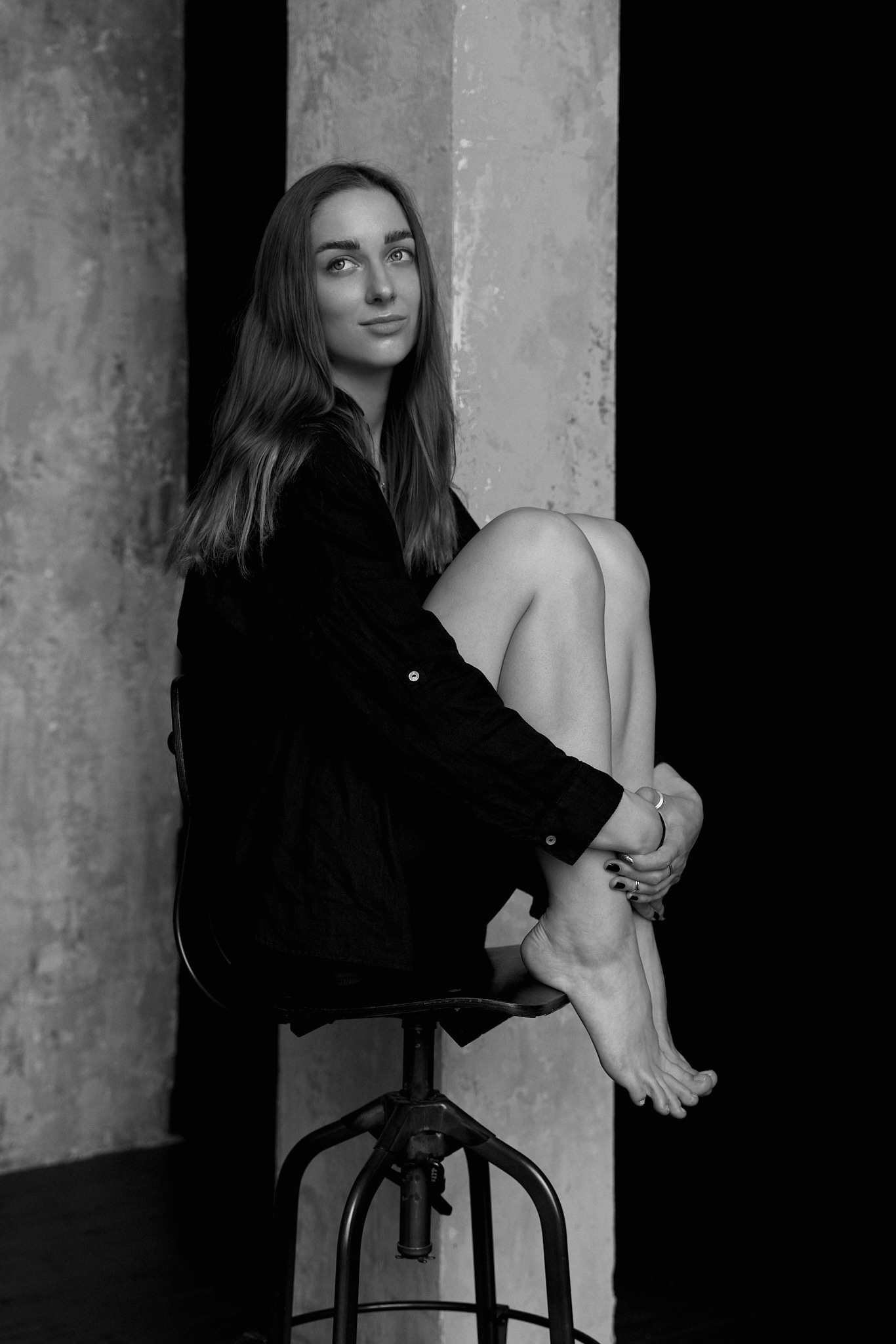 a woman sitting on a chair in a studio black and white