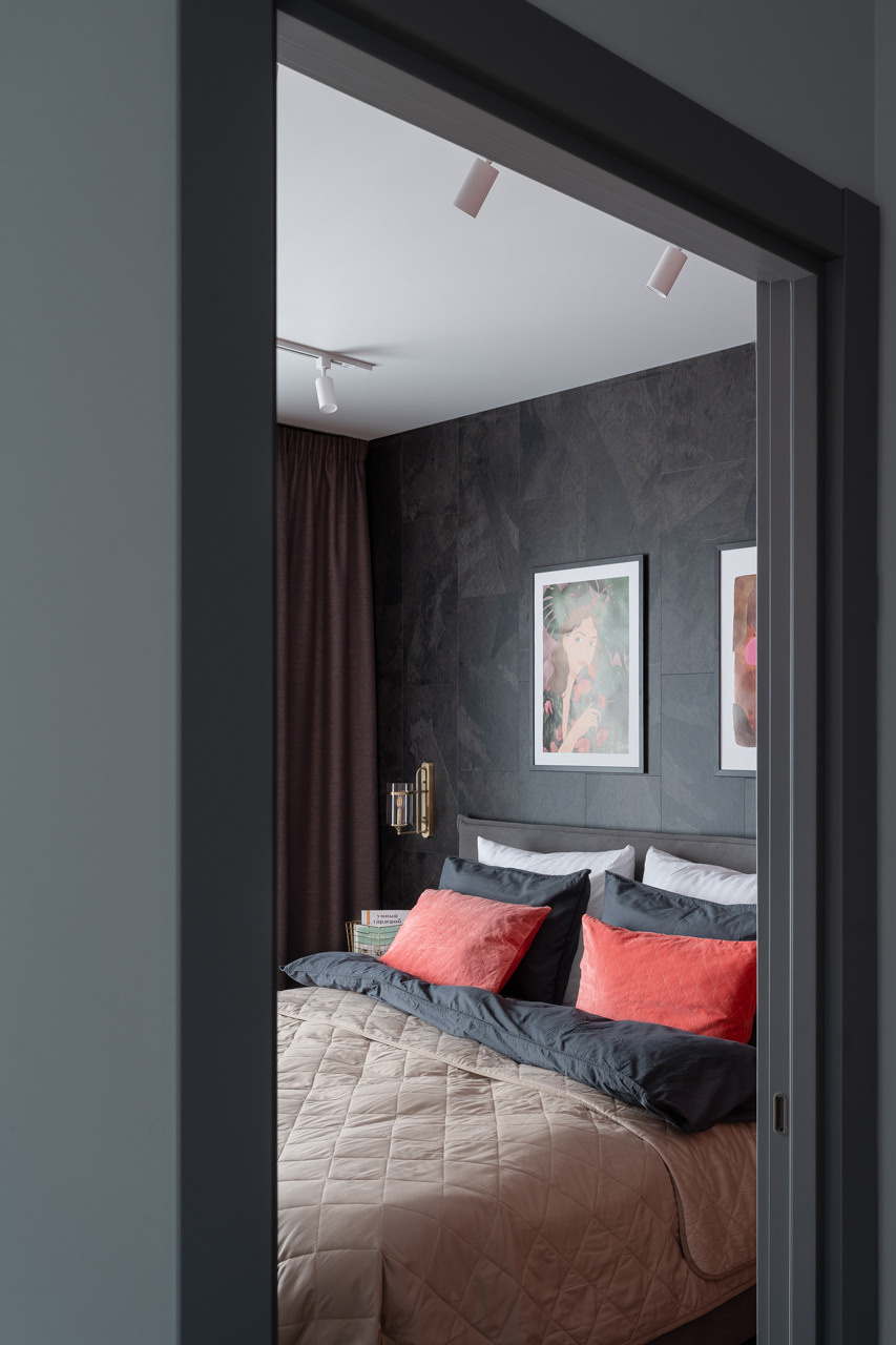 Спальня с акцентной стеной, винтажным комодом и большим зеркалом.