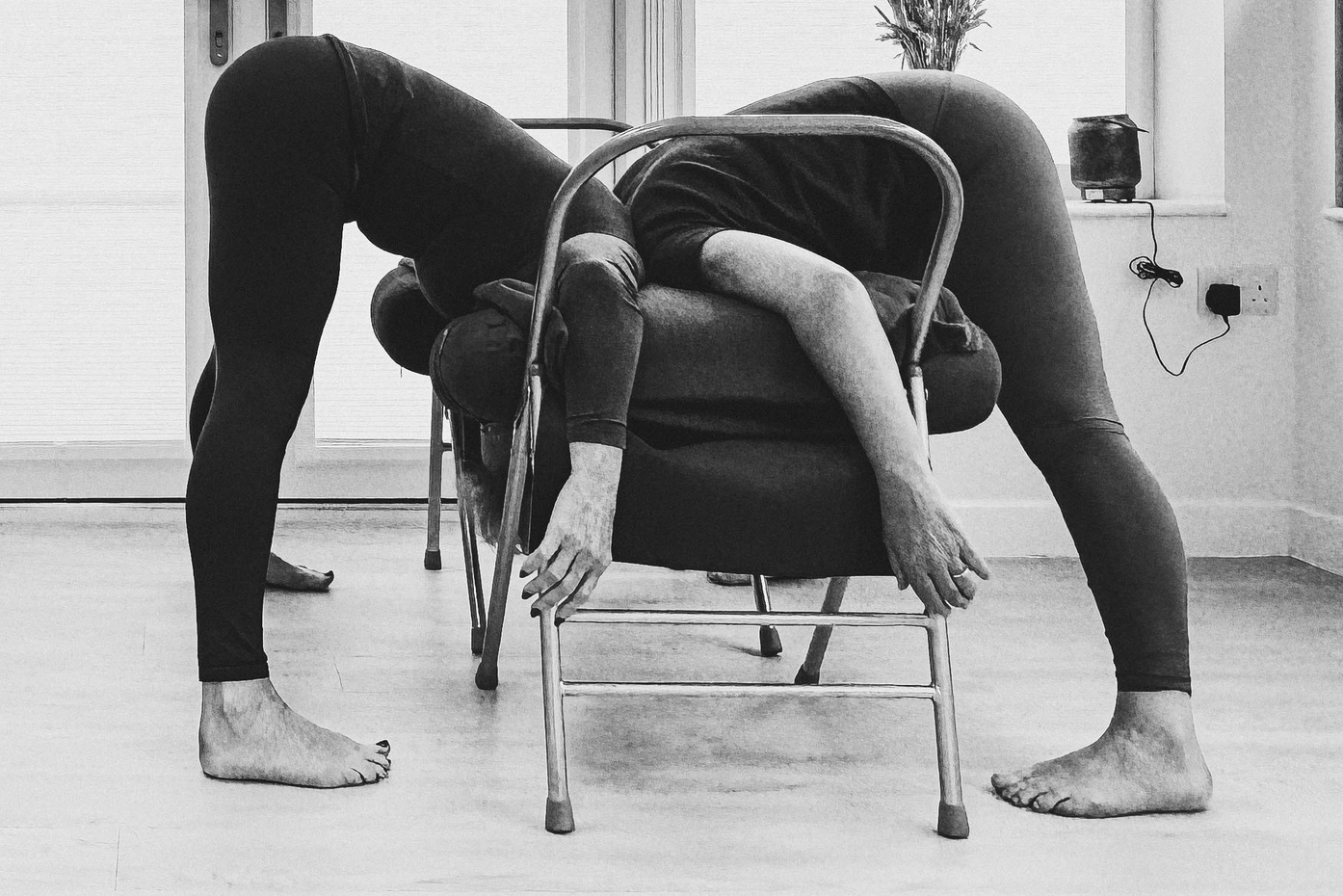 Student practising supported Iyengar yoga forward bend with chair and bolsters in Solihull.