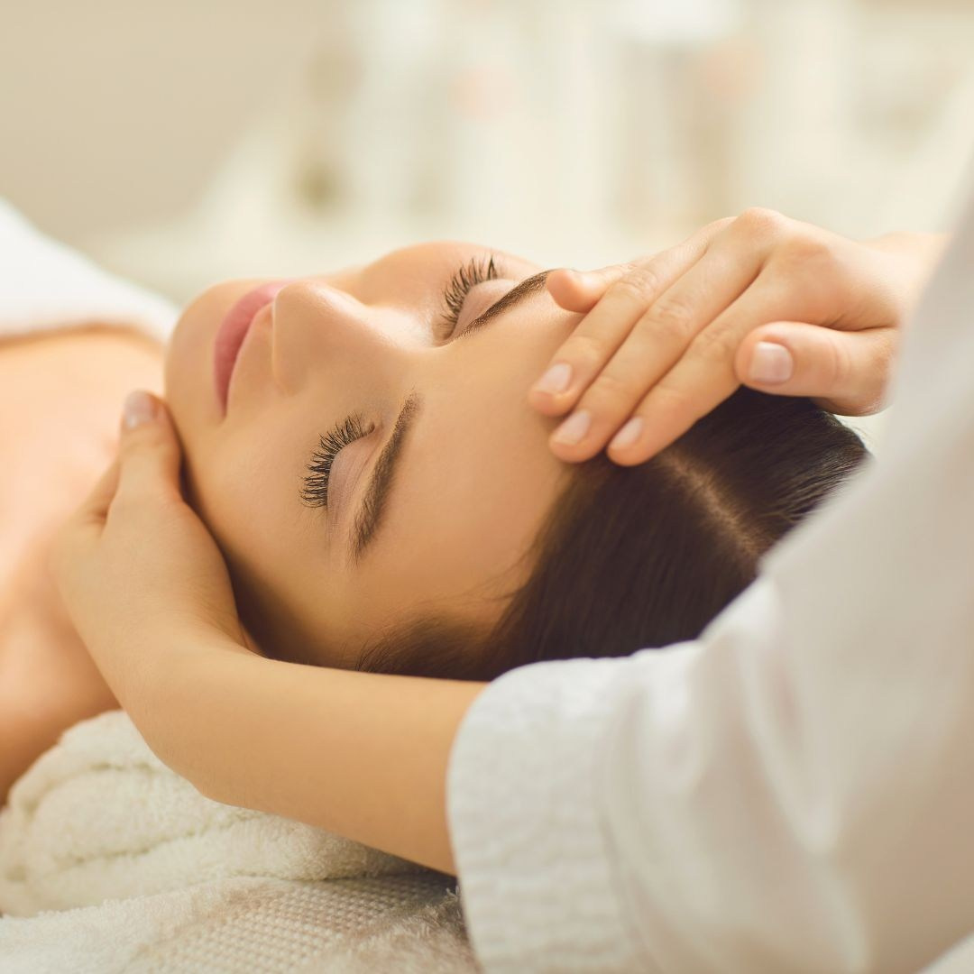 Eine Masseurin massiert eine Frau, die mit geschlossenen Augen liegt und sich entspannt