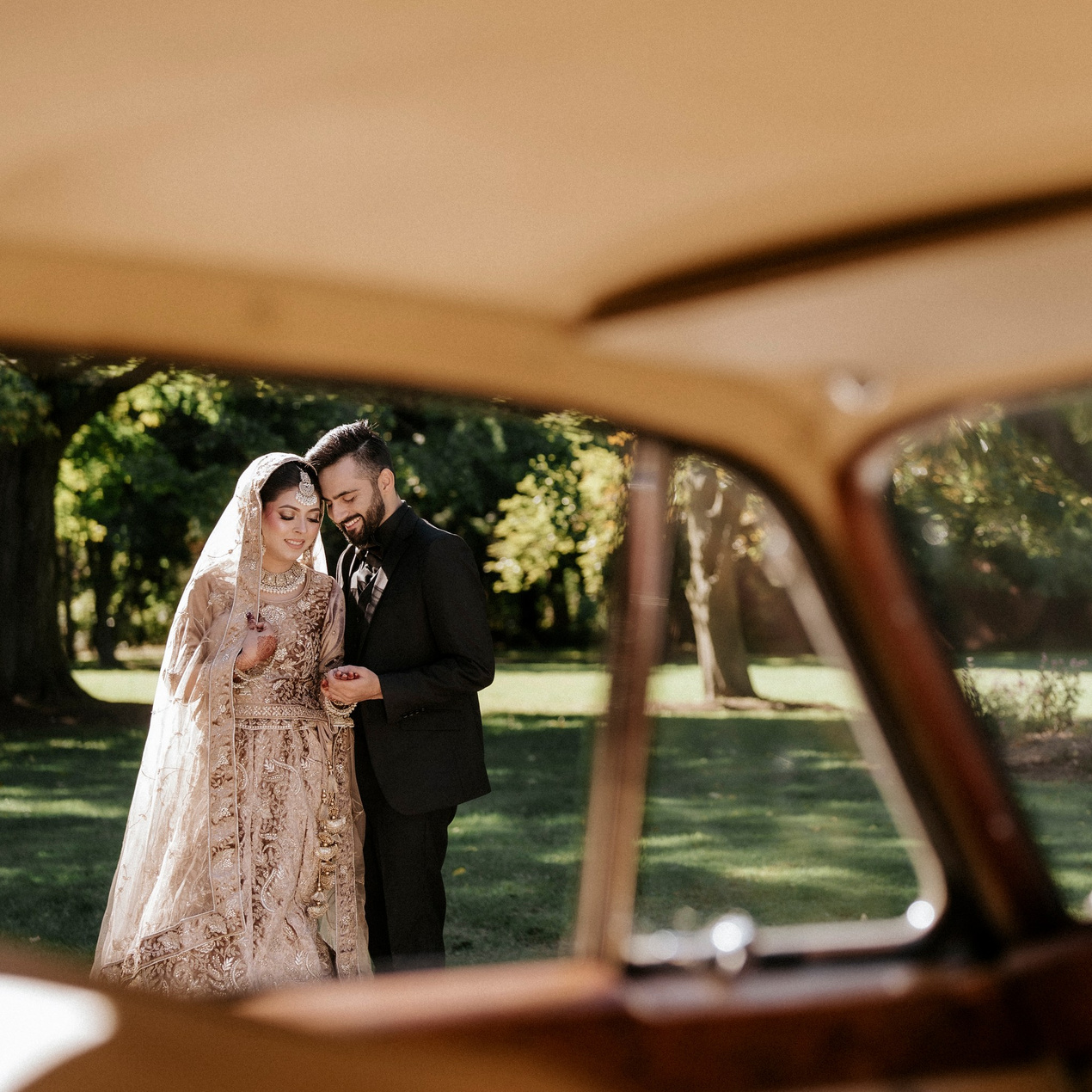 Bride adjusting her earrings inside a vintage car before Indian-Pakistani wedding ceremony