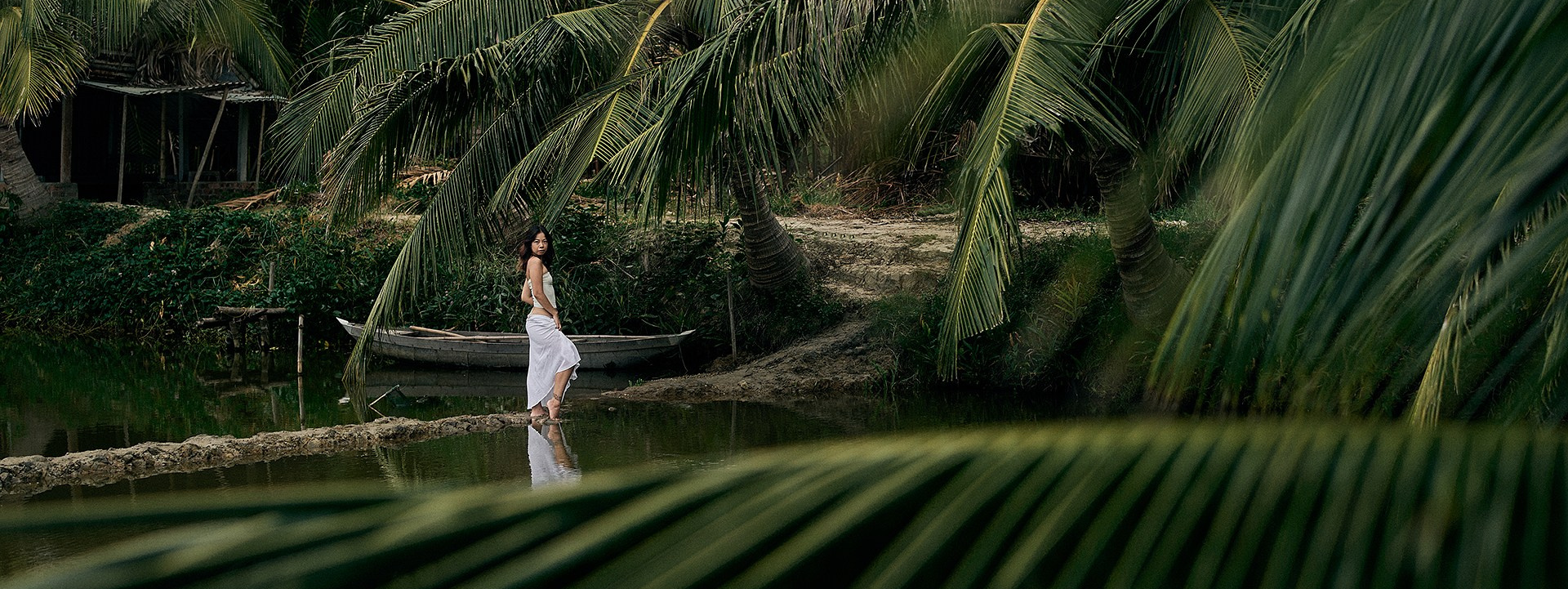 A young woman amidst coconut palms during a photoshoot in Hoi An.