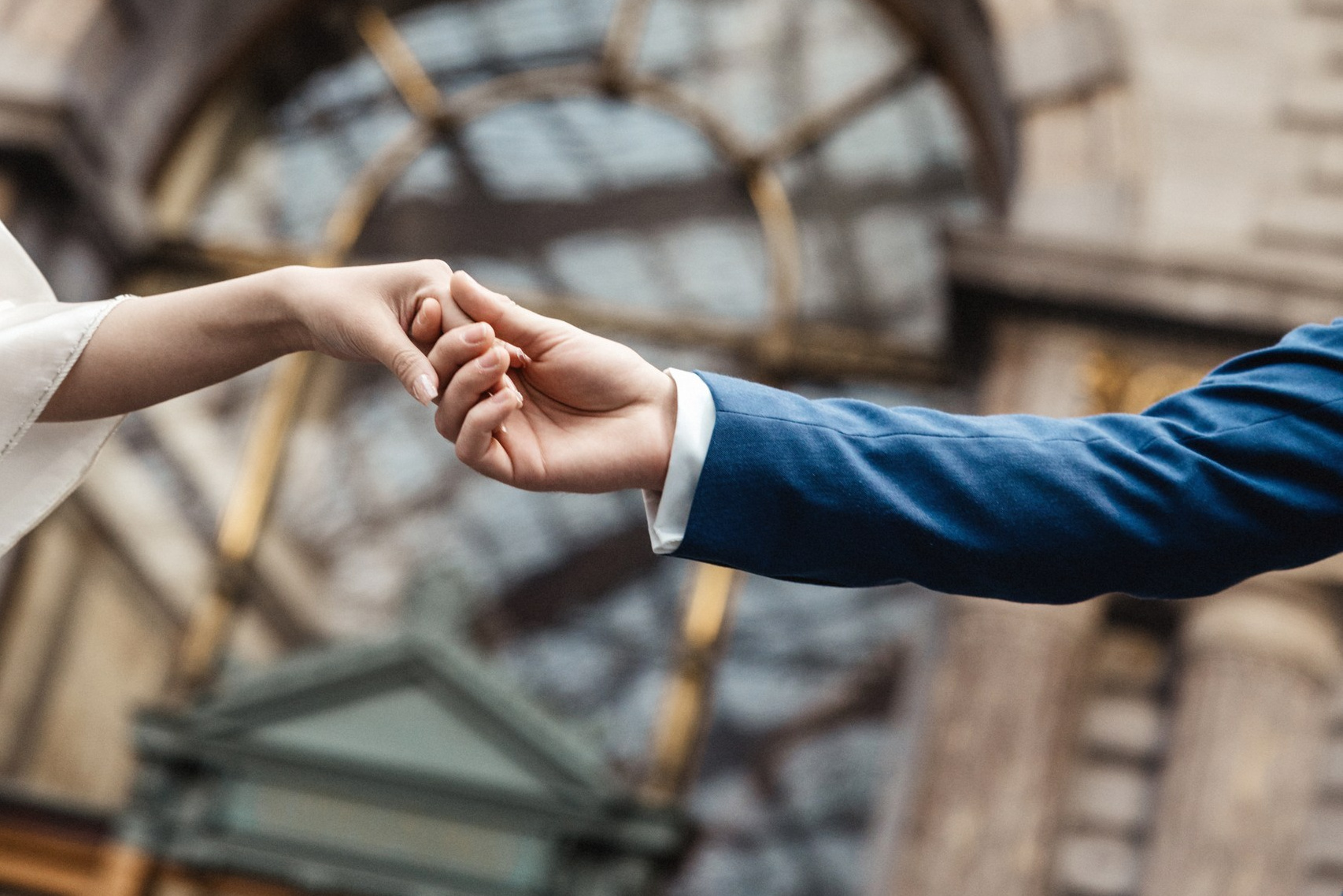 Een koppel houdt elkaars hand vast tijdens een trouwshoot bij Antwerpen-Centraal.