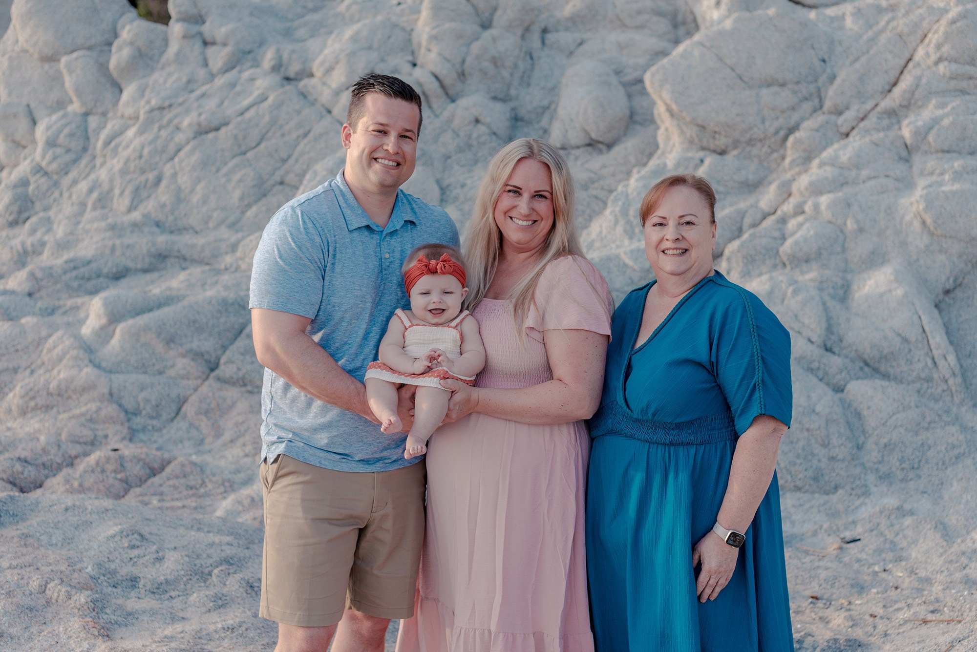 Three generations of a family posing in front of rocks on a Los Cabos beach