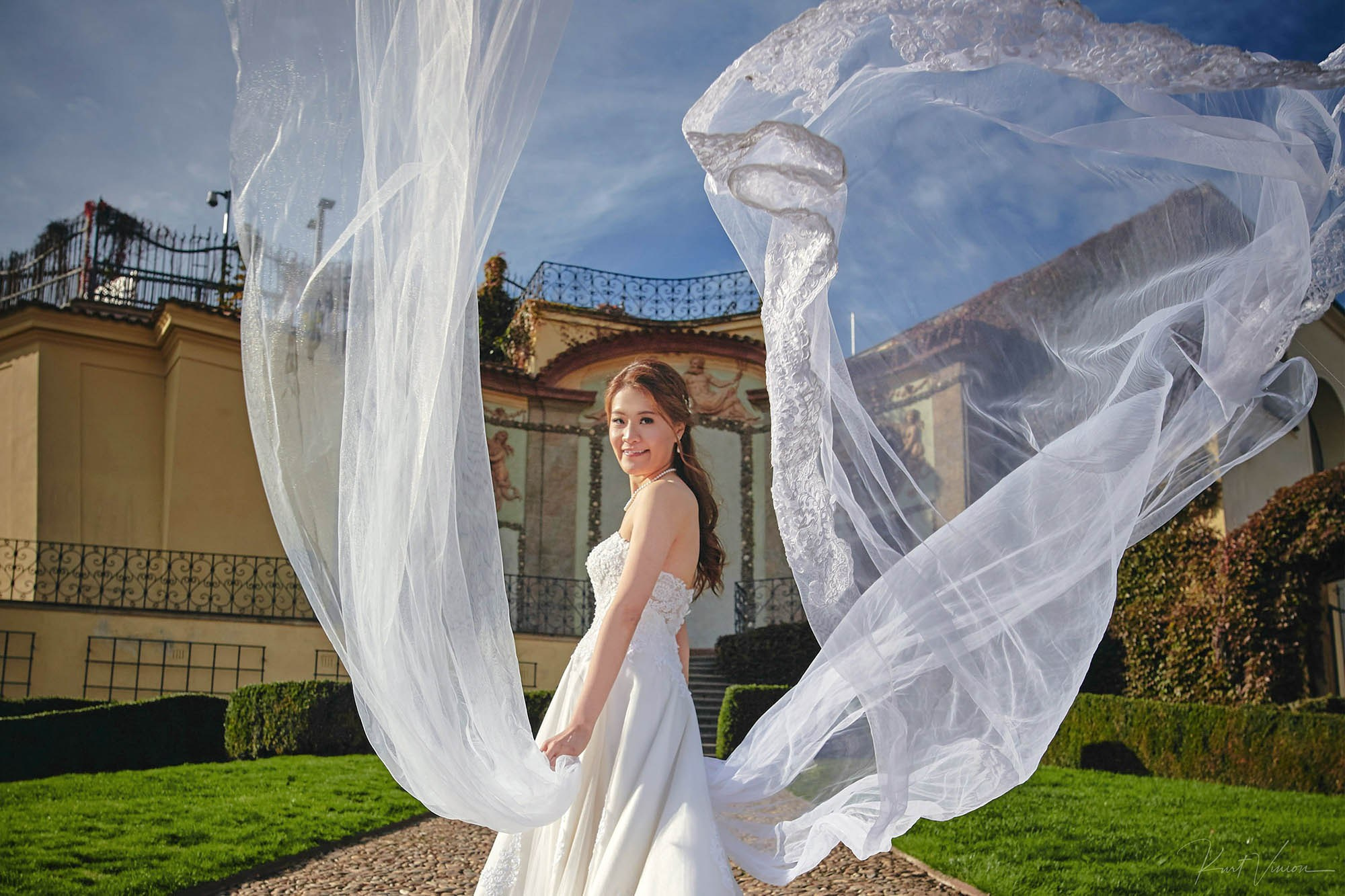 Bride with flowing veils looking back at the Vrtba Garden wind.