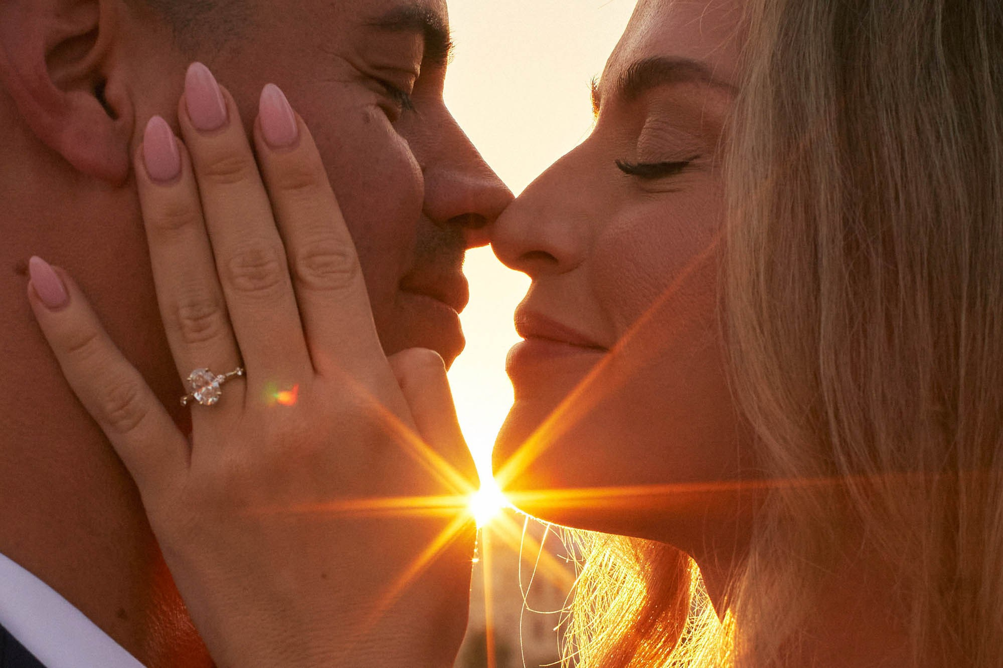 A beautiful blonde-haired woman lovingly embraces her partner's smiling face.