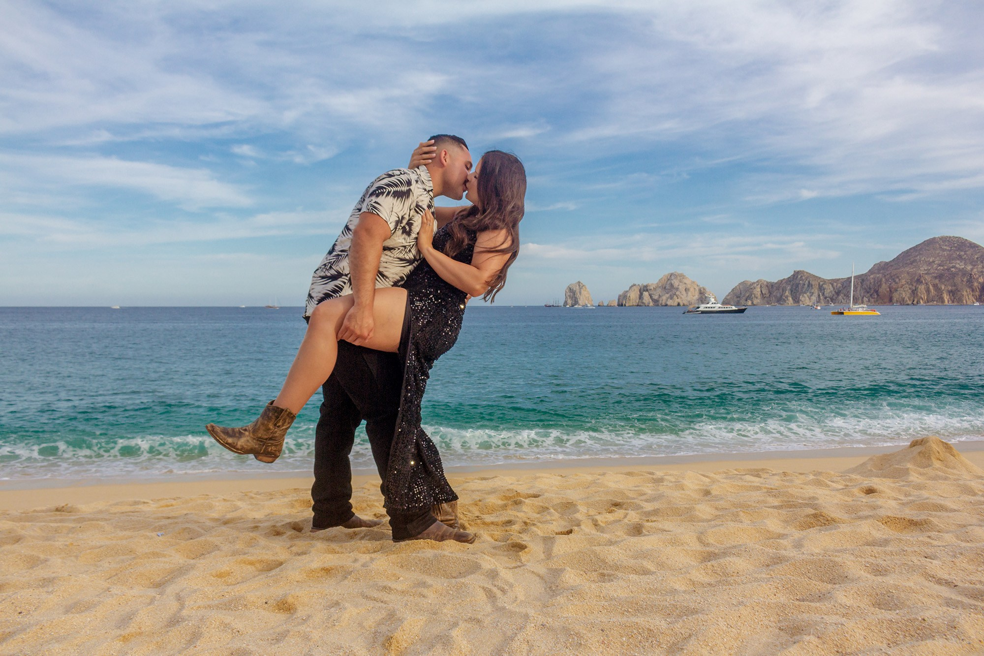 Couple dancing on the beach at sunset, her in a black sequin dress
