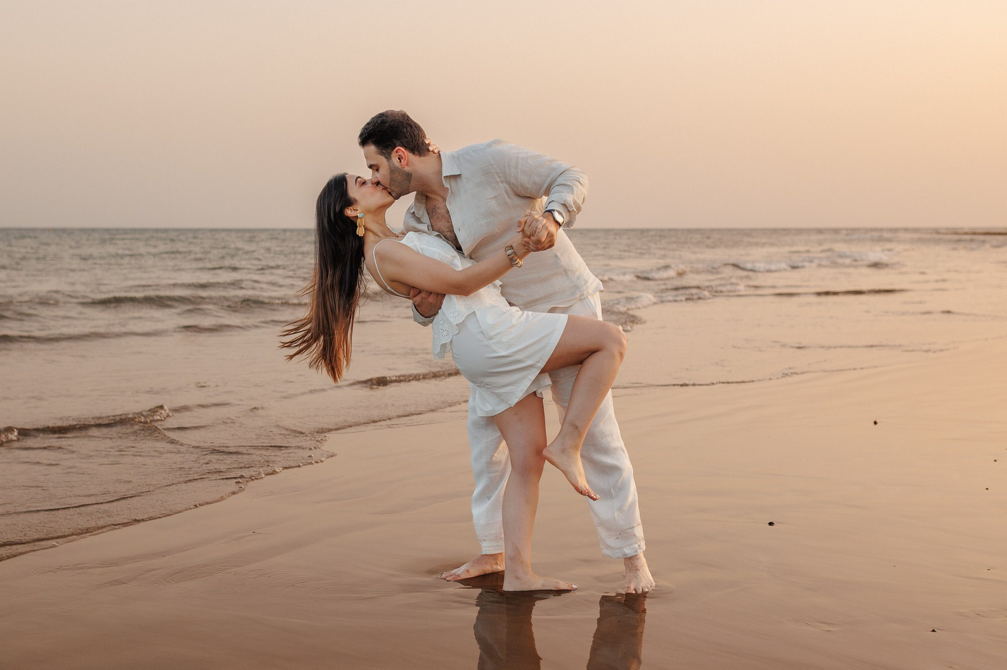 Couple kissing on the beach at sunset with fishing boats, Las Palmas