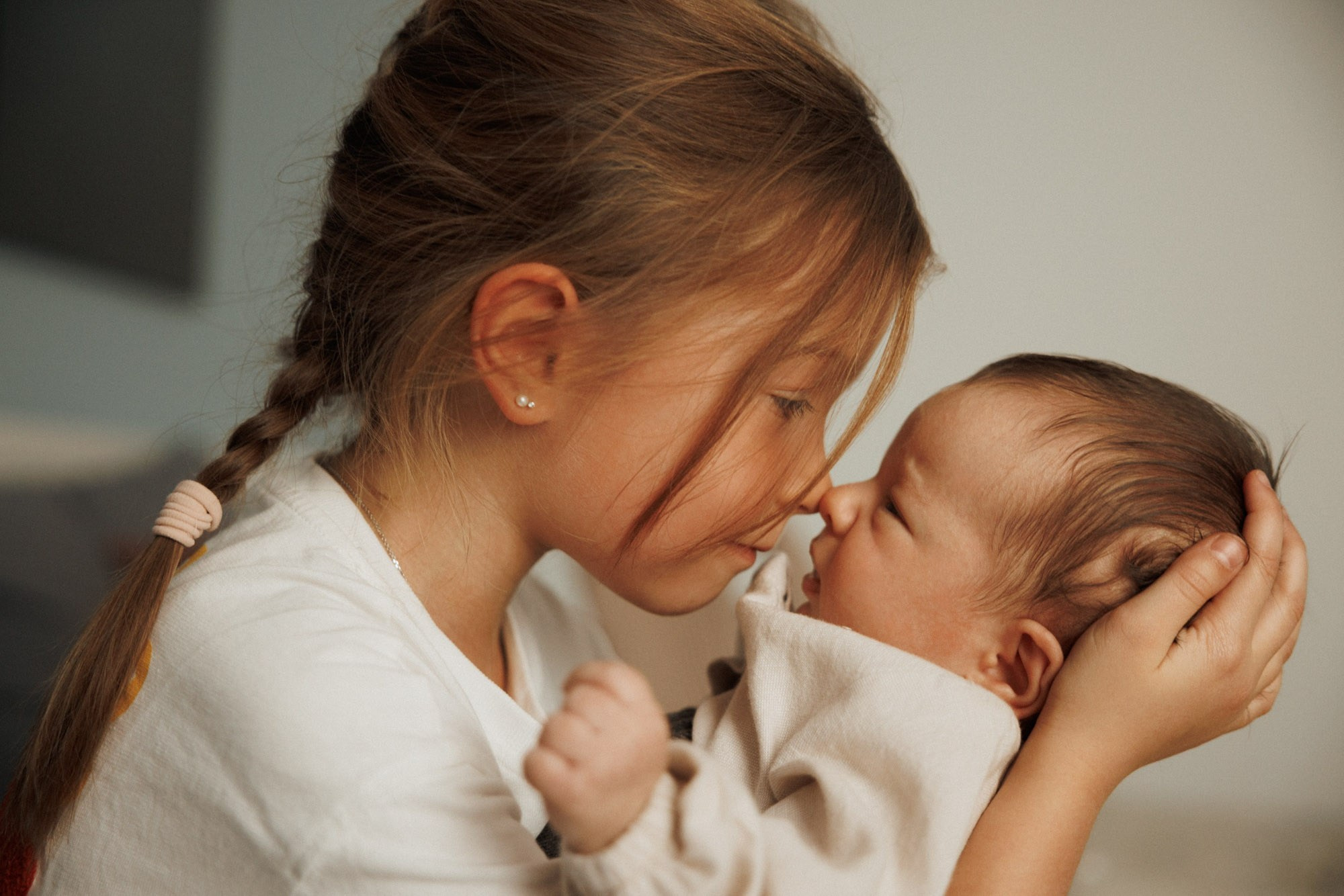 Older sister touching noses with her newborn sibling at home in Montreal