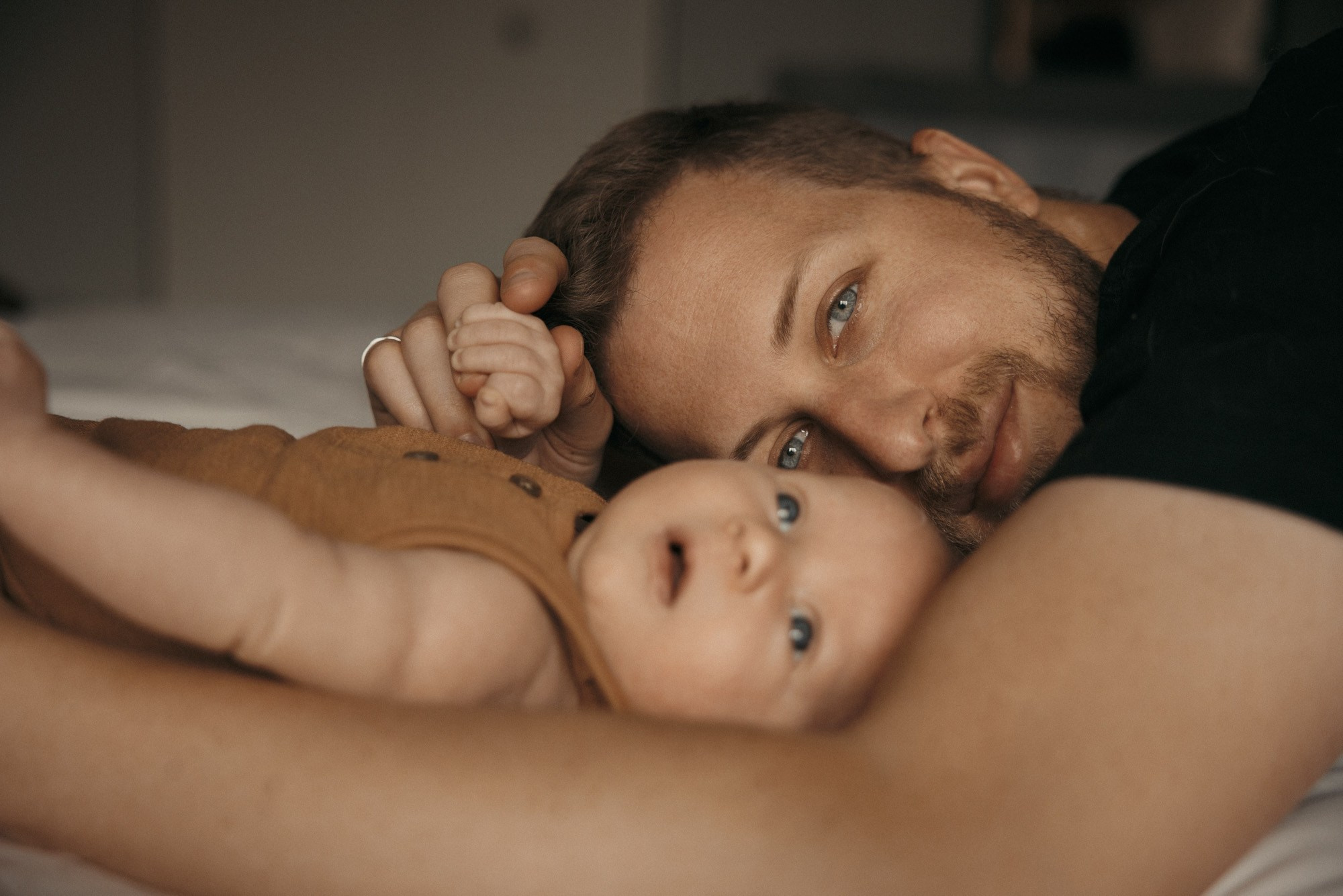 Father lying face-to-face with his newborn during a quiet at-home session in Montreal