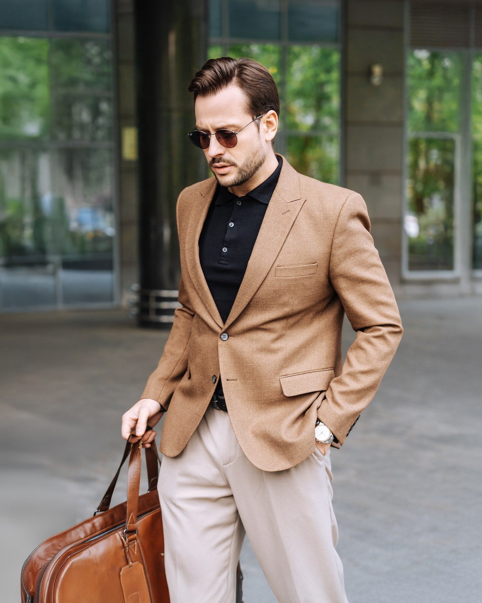 Деловой мужчина с кожаной сумкой у входа в бизнес-отель