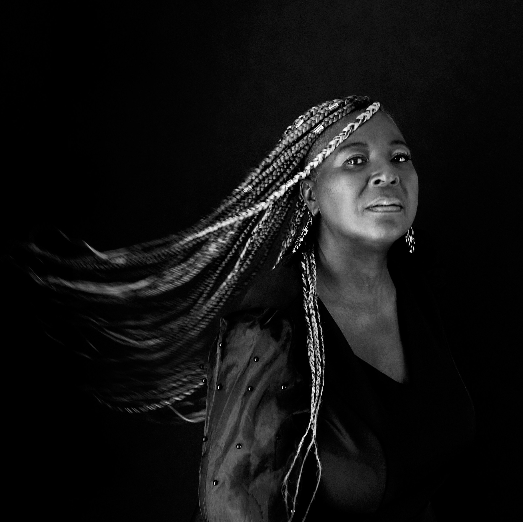 BLACK WOMAN WITH BRAIDS SWINGING TO SIDE LOOKING AT CAMERA 