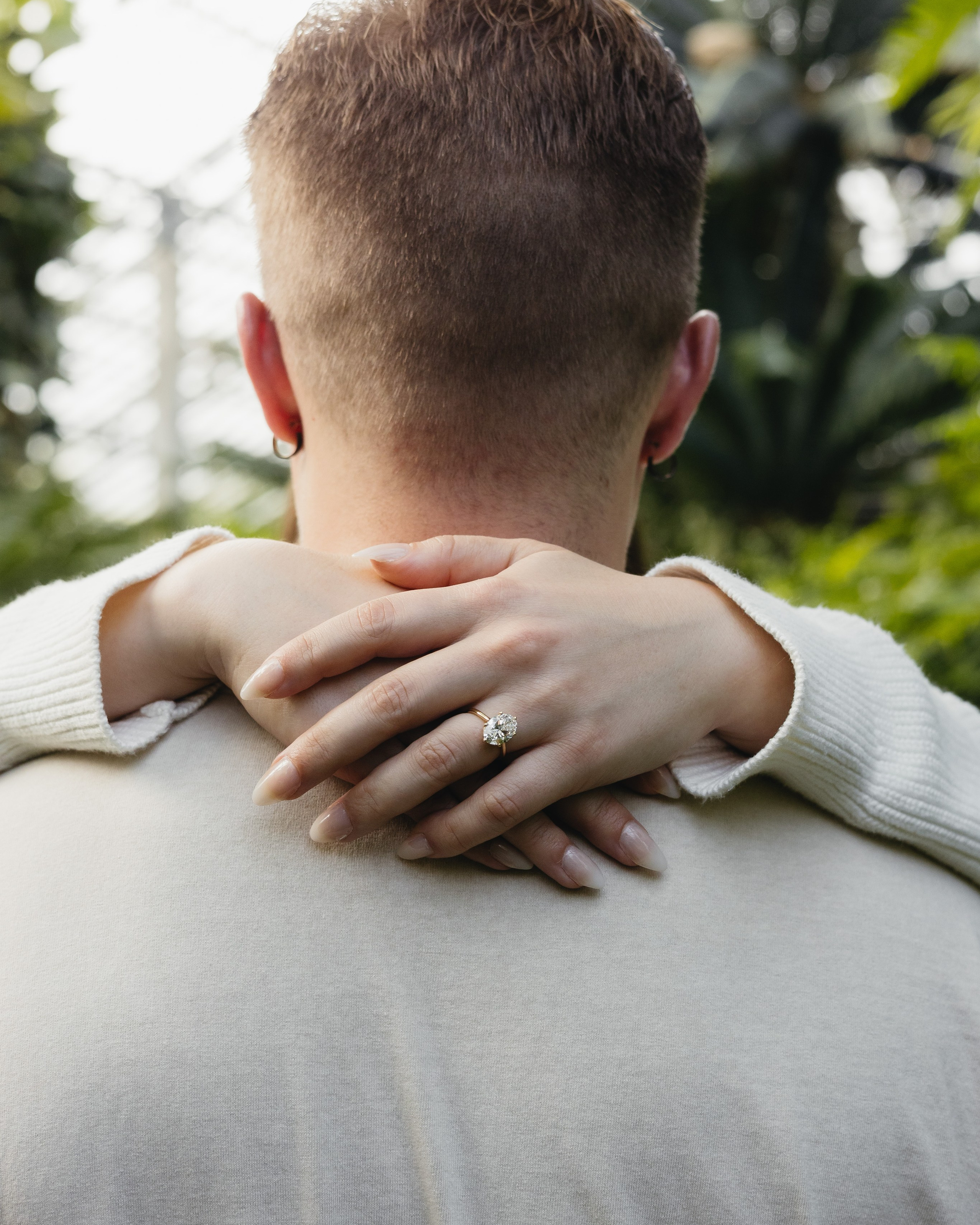 Fiancée holding her partner's neck showing engagement ring during proposal at Garfield Park Conservatory