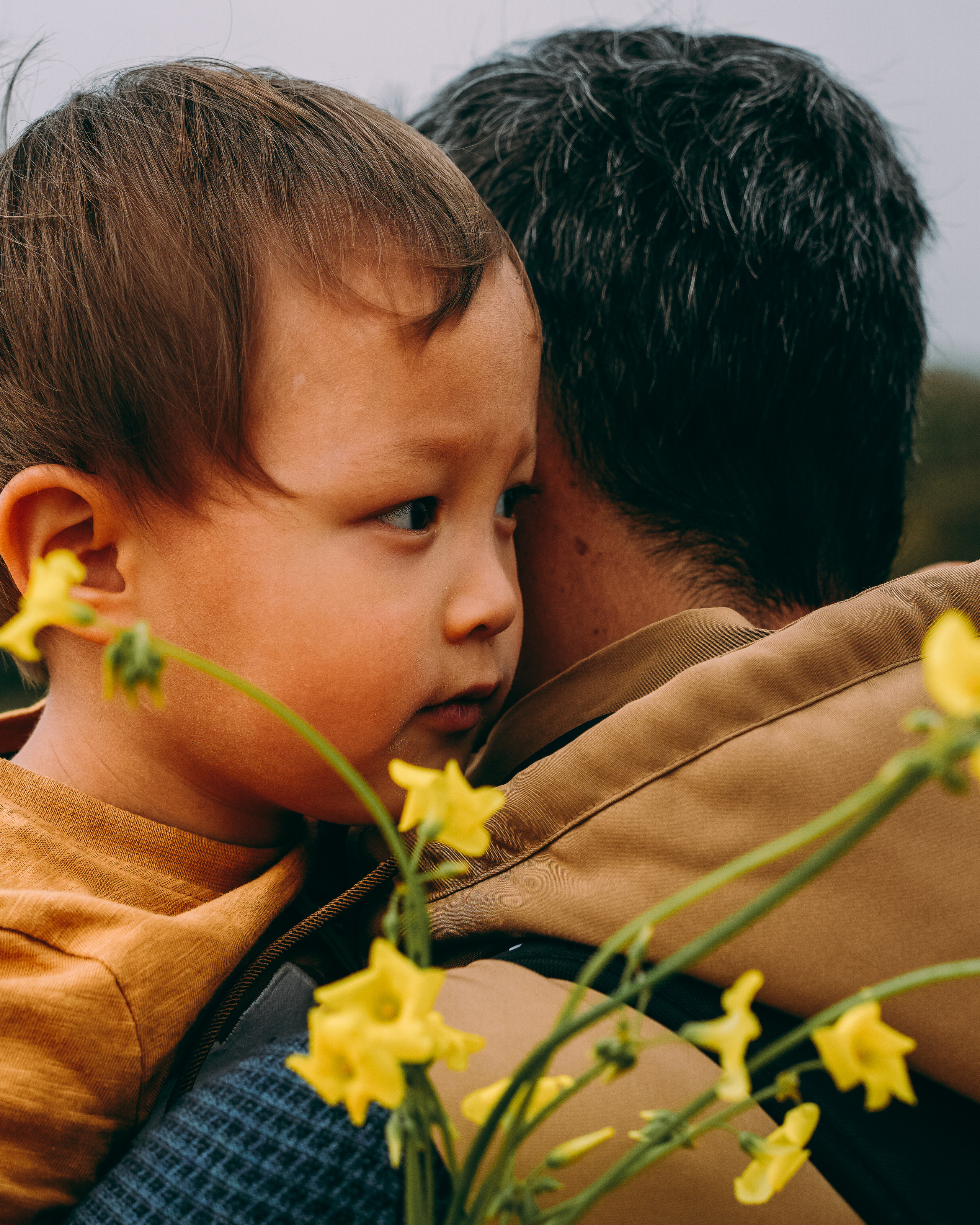 Dad is hugging his son with yellow flowers hugging. Family photo shoot. 