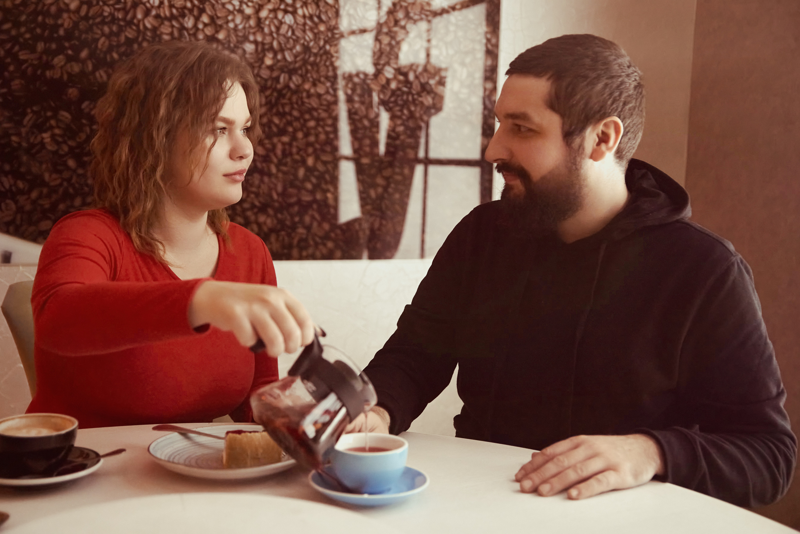 Девушка наливает чай своему парню в кафе.