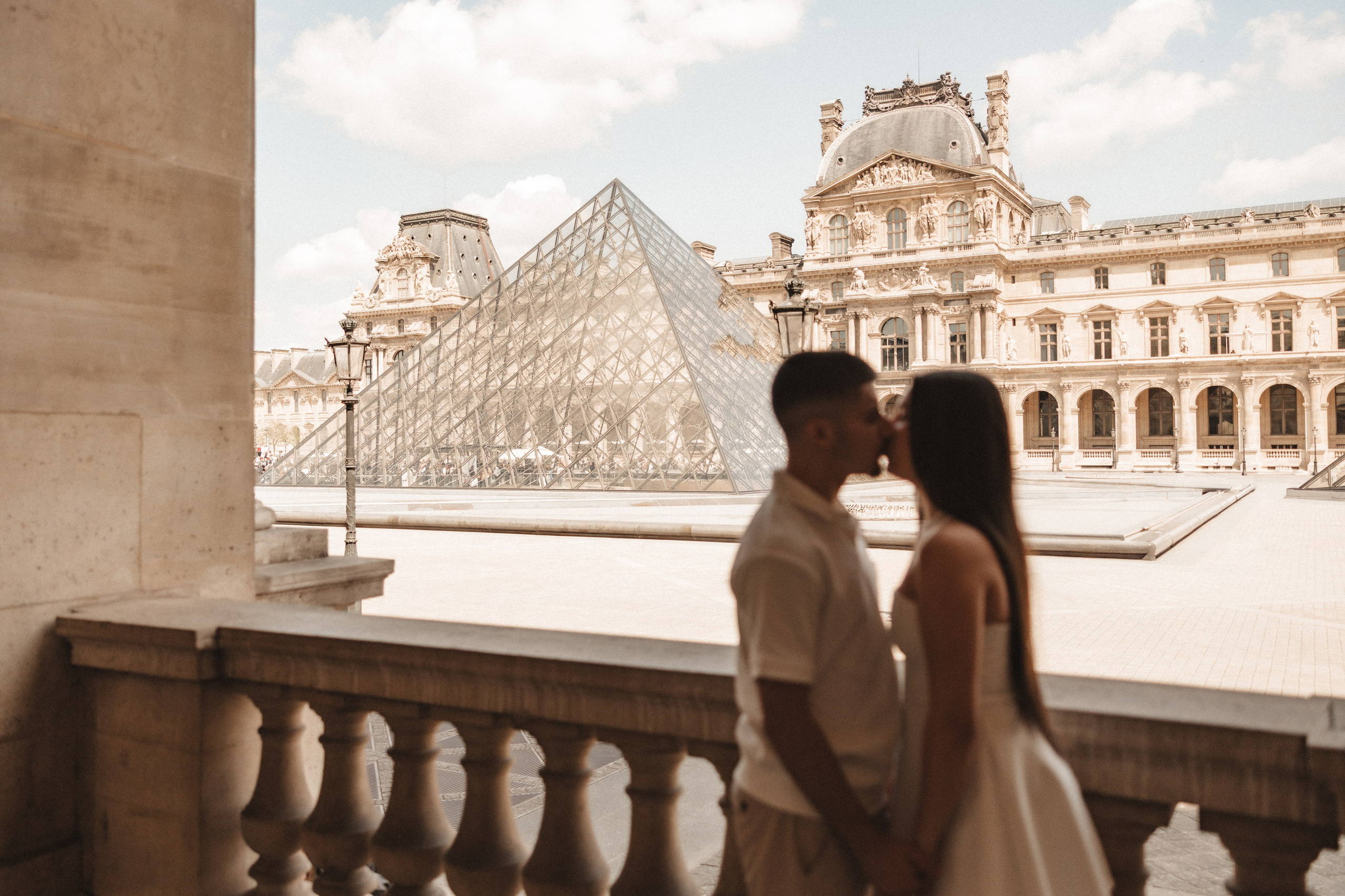 Casal de noivos beijando-se em frente ao Louvre, em Paris, França