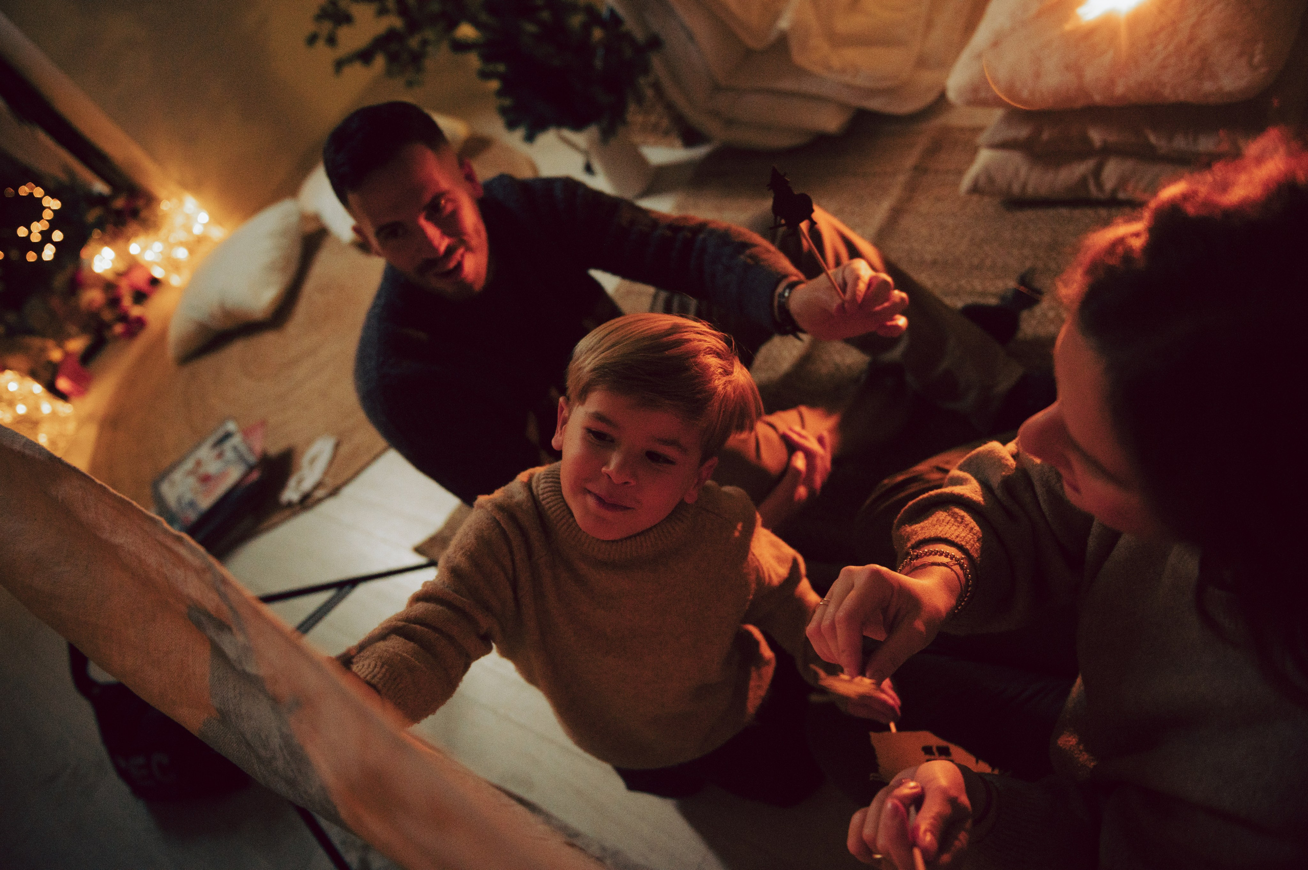 Un momento familiare pieno di poesia: genitori e bambino danno vita a un teatrino delle ombre dietro un telo illuminato da una luce calda. Le sagome fatte a mano, l’atmosfera invernale e i dettagli natalizi trasformano questa scena in un ricordo intimo e creativo da custodire. servizio fotografico natalizio famiglia, teatrino delle ombre, gioco creativo bambini, atmosfera intima natalizia, luce calda inverno, fotografia di famiglia creativa, racconti di Natale, connessione genitori figli, pupazzi fatti a mano, anastasiia buchinskaia photographer, anamilanofoto