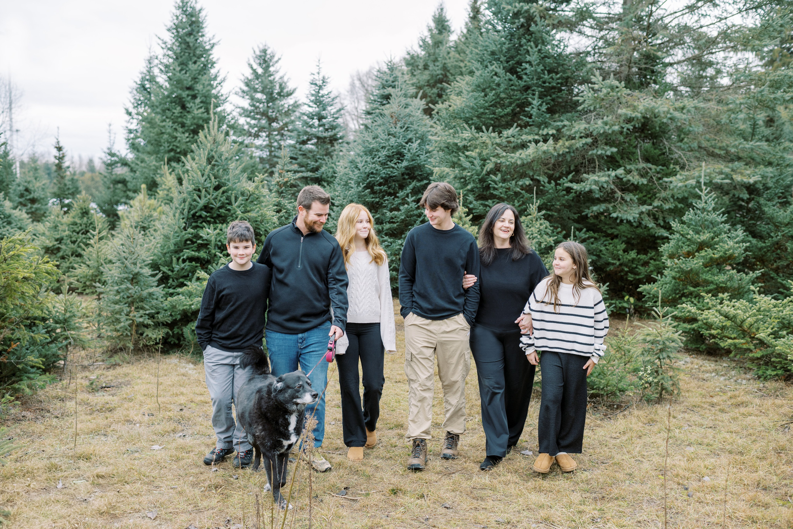family photo of parents and 4 children and black lab dog 