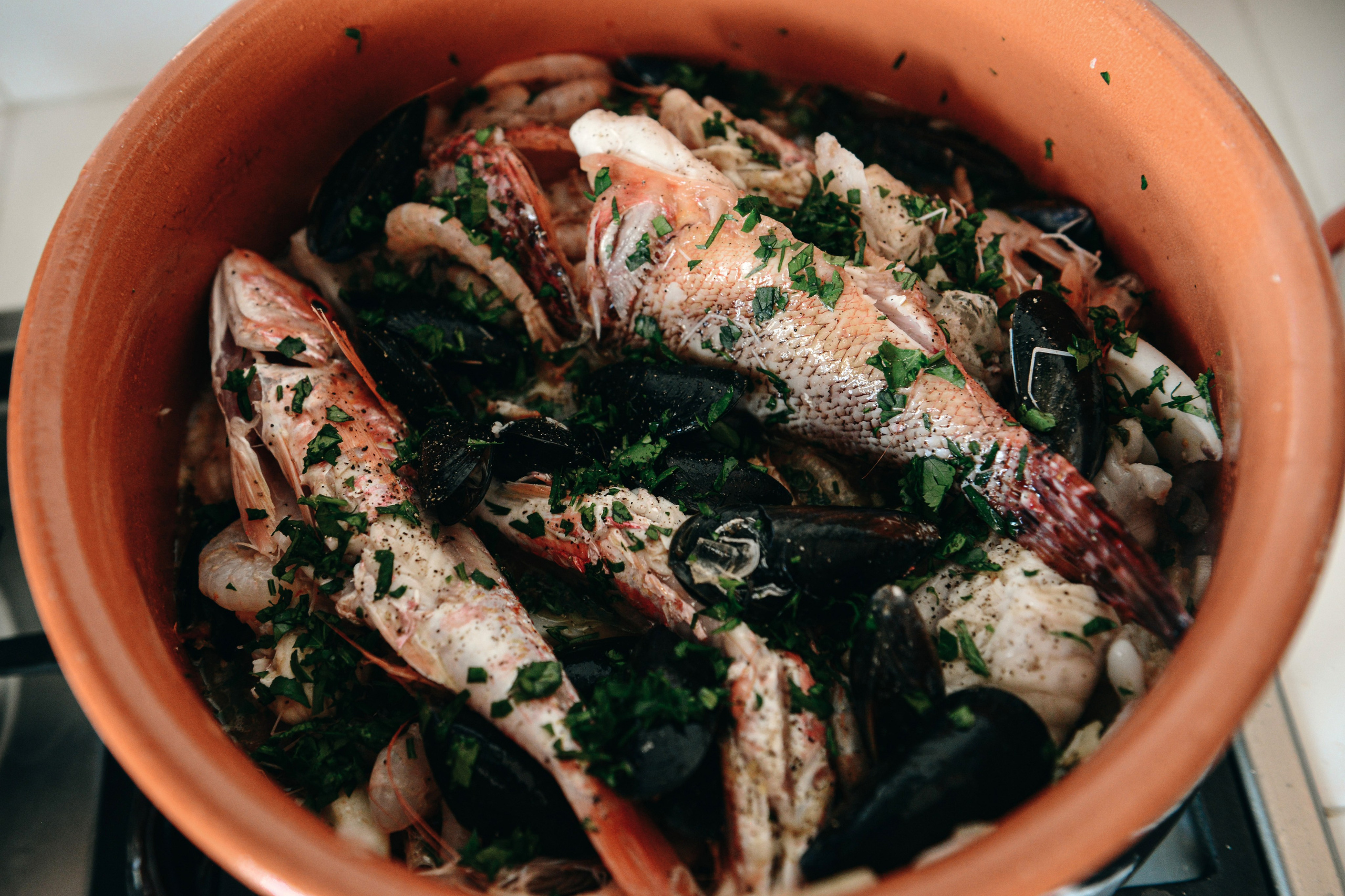 Traditional zuppa di pesce — fish, mussels, shrimp, and herbs slow-cooked in a clay pot.