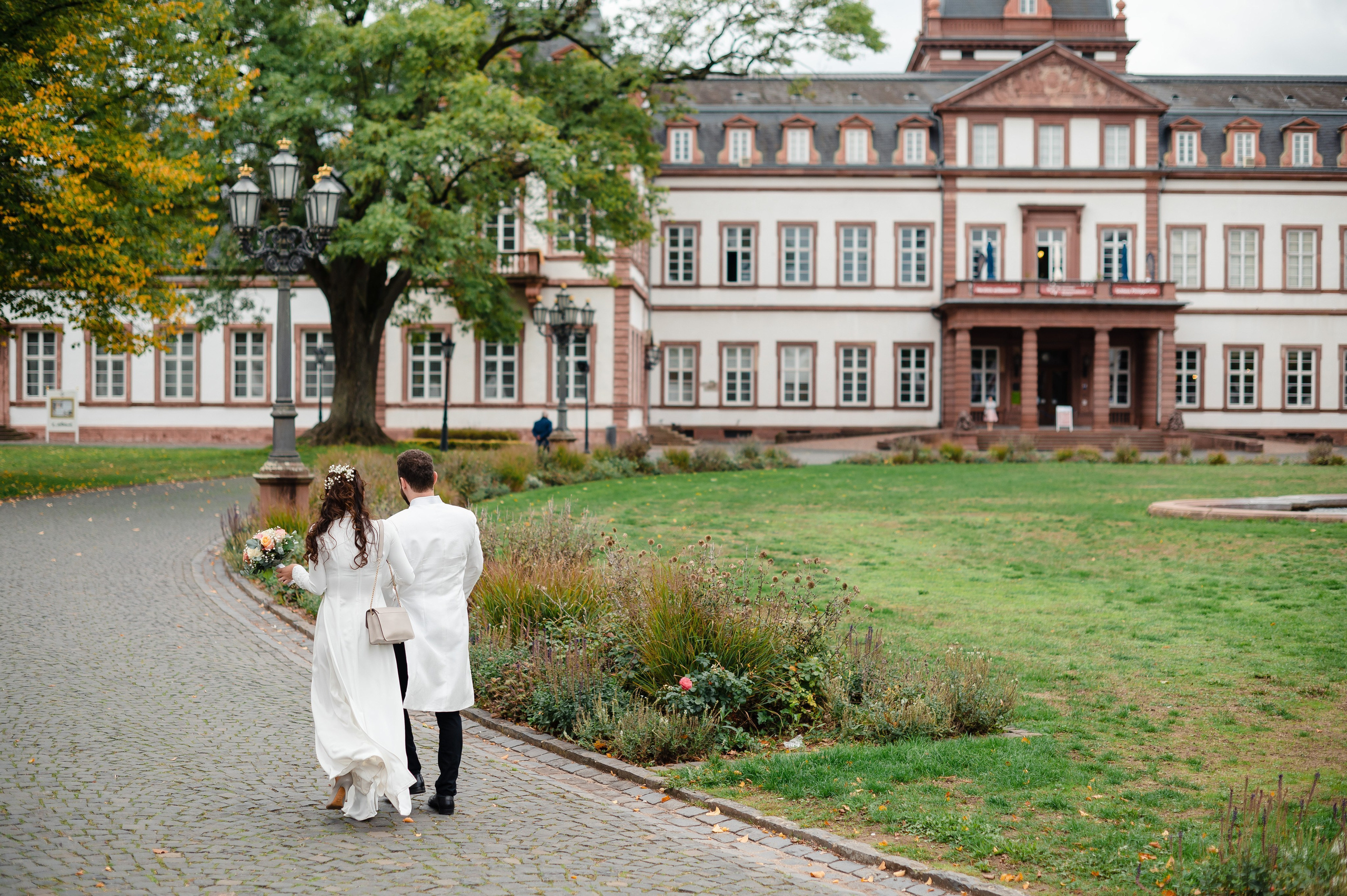 Hochzeitsfoto eines Brautpaares mit Schloss Philippsruhe im Hintergrund
