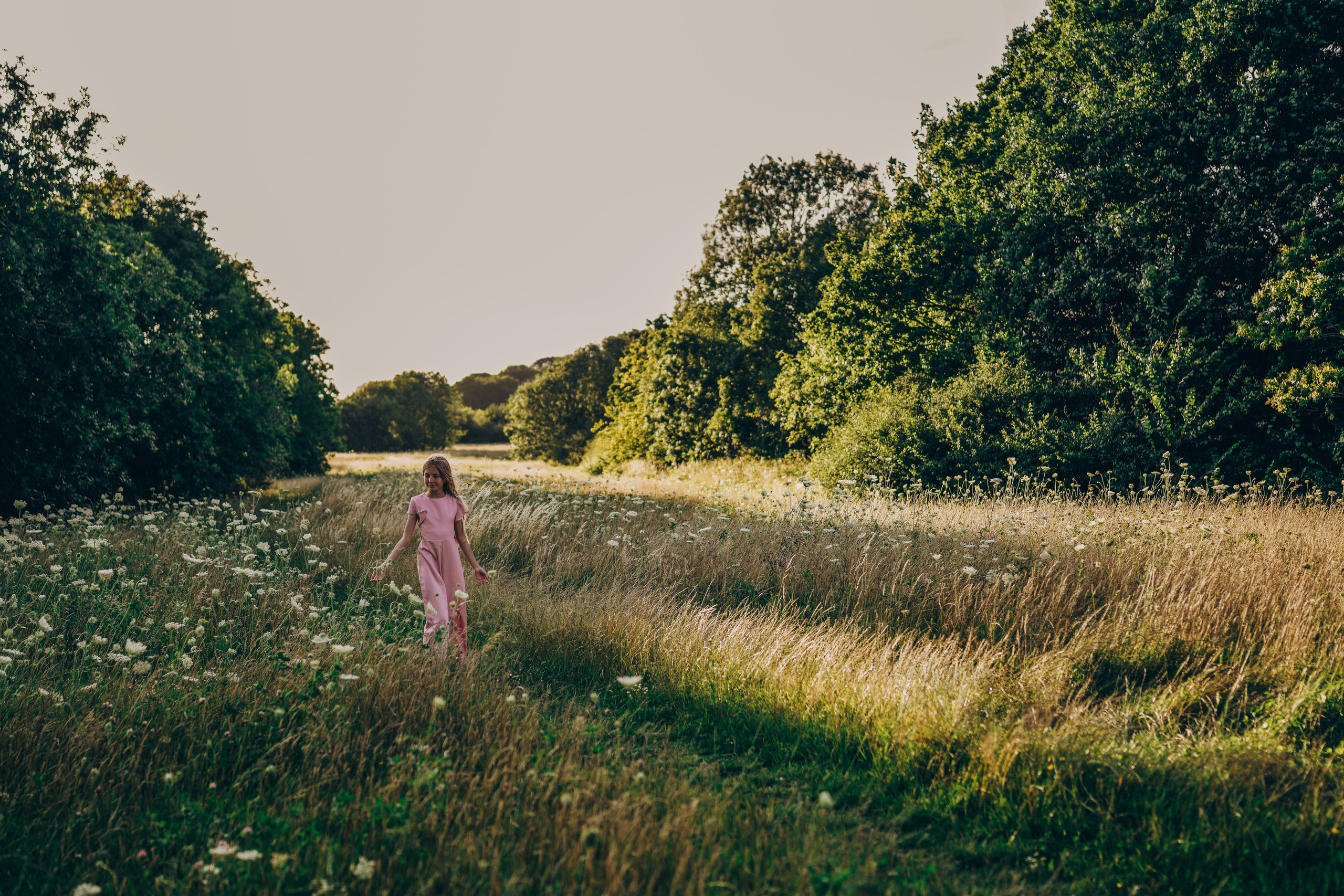 Mother walking with child through green meadow at Hillfield Park Solihull, relaxed outdoor family photography in nature