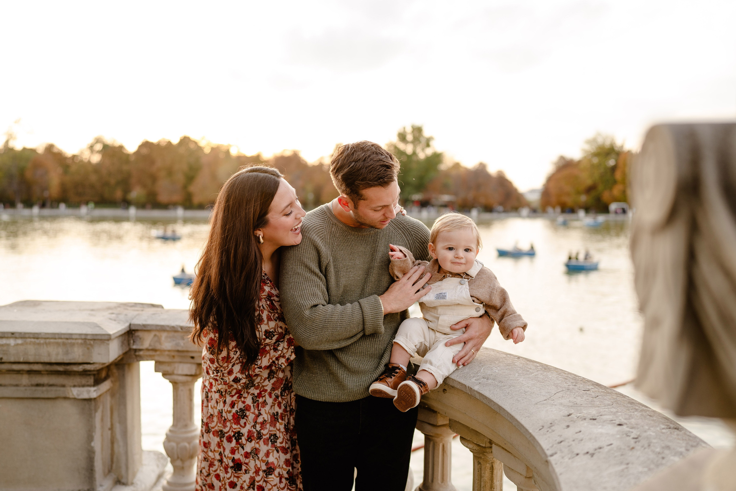 Couple with baby enjoying sunset in Retiro park.