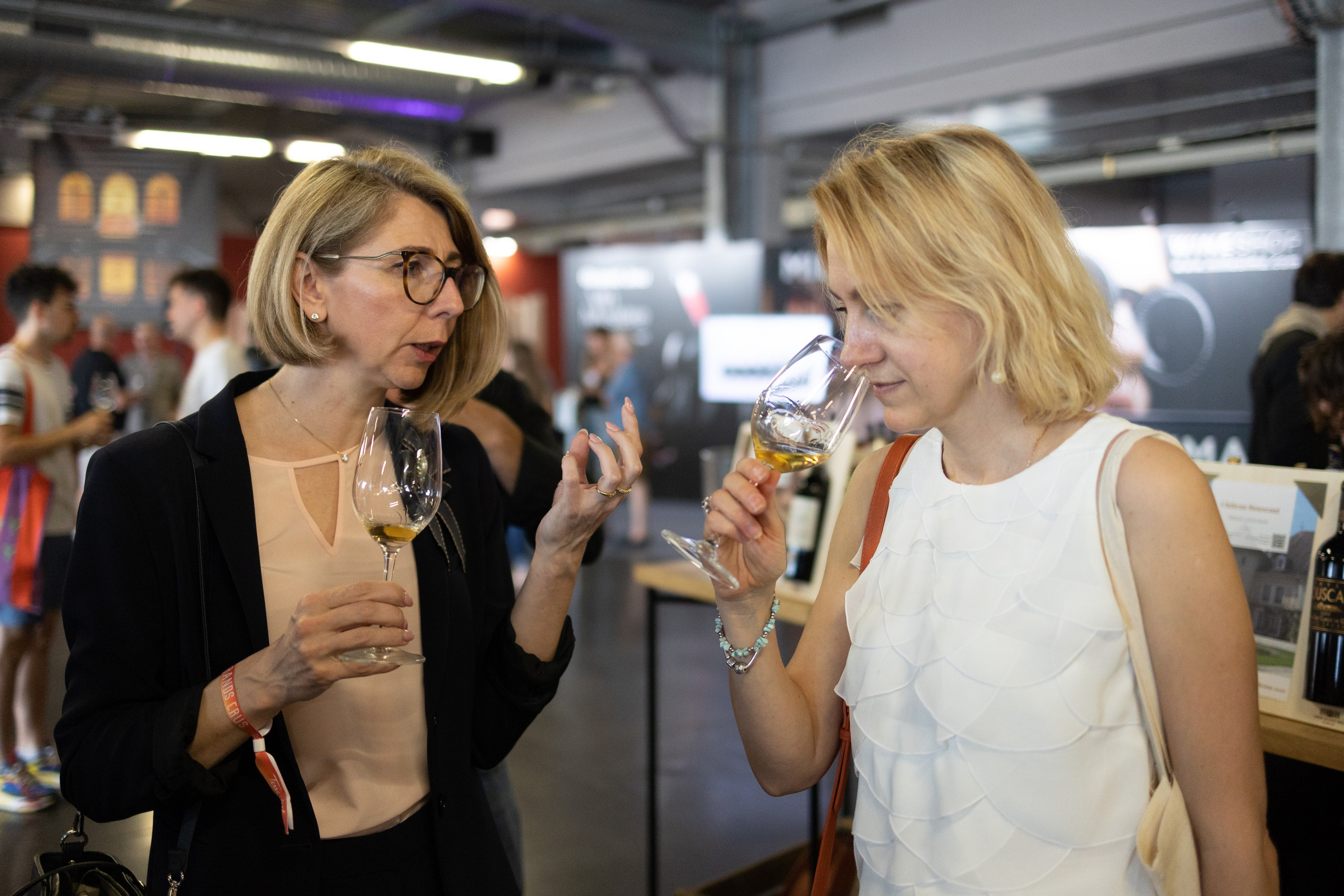 two guests talking with glasses in hand during a networking event