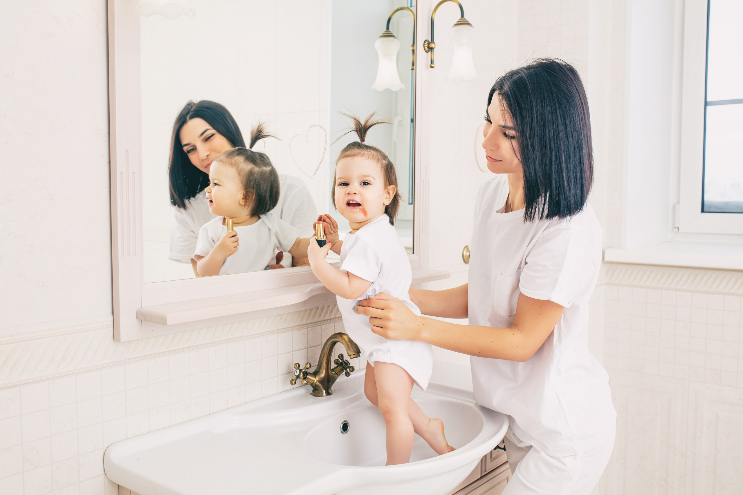 Routine matinale mère-fille, coiffure et sourires complices dans une salle de bain lumineuse