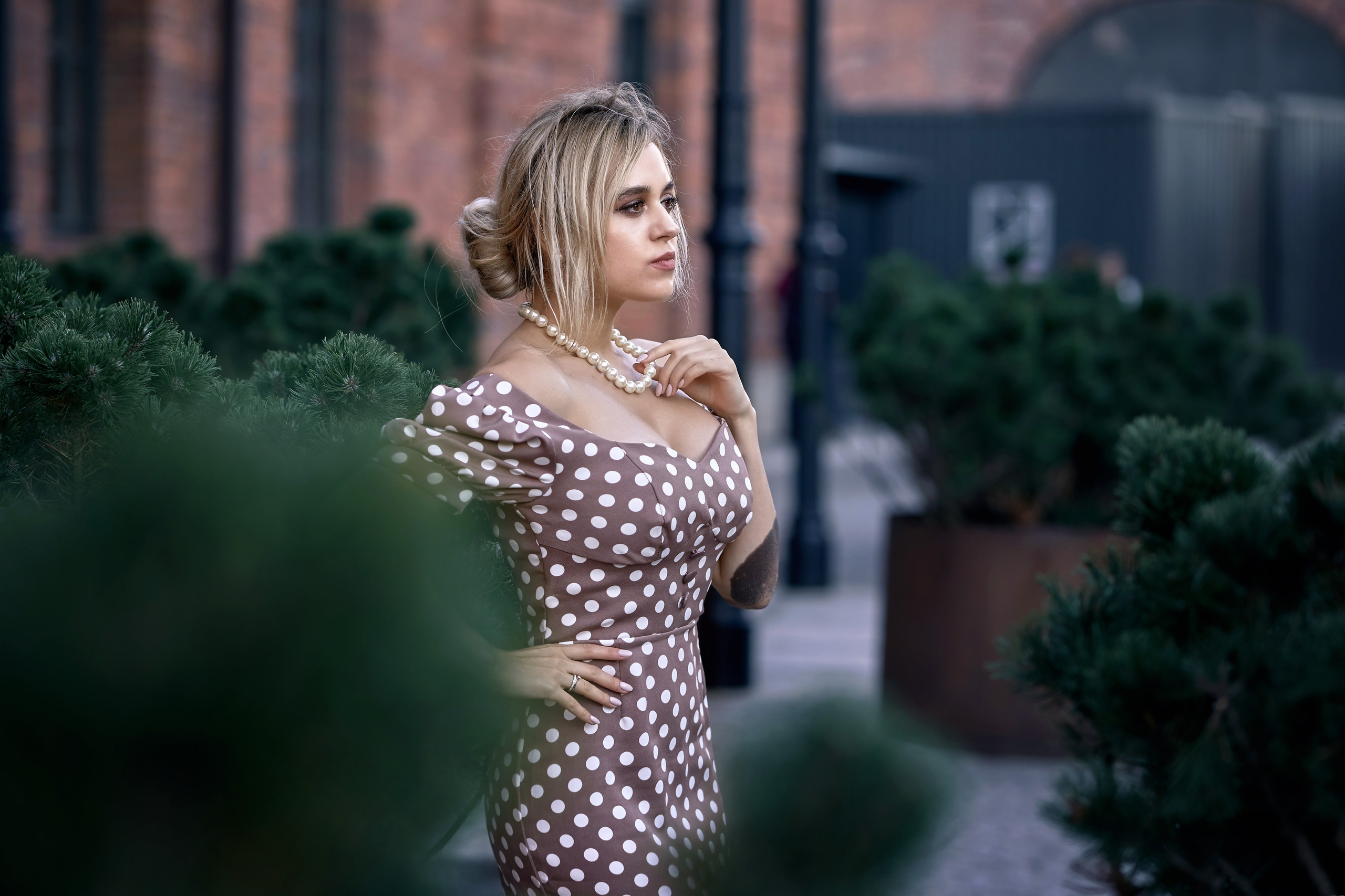 Woman with a beautiful hairstyle in a summer dress in a garden during an outdoor photo session