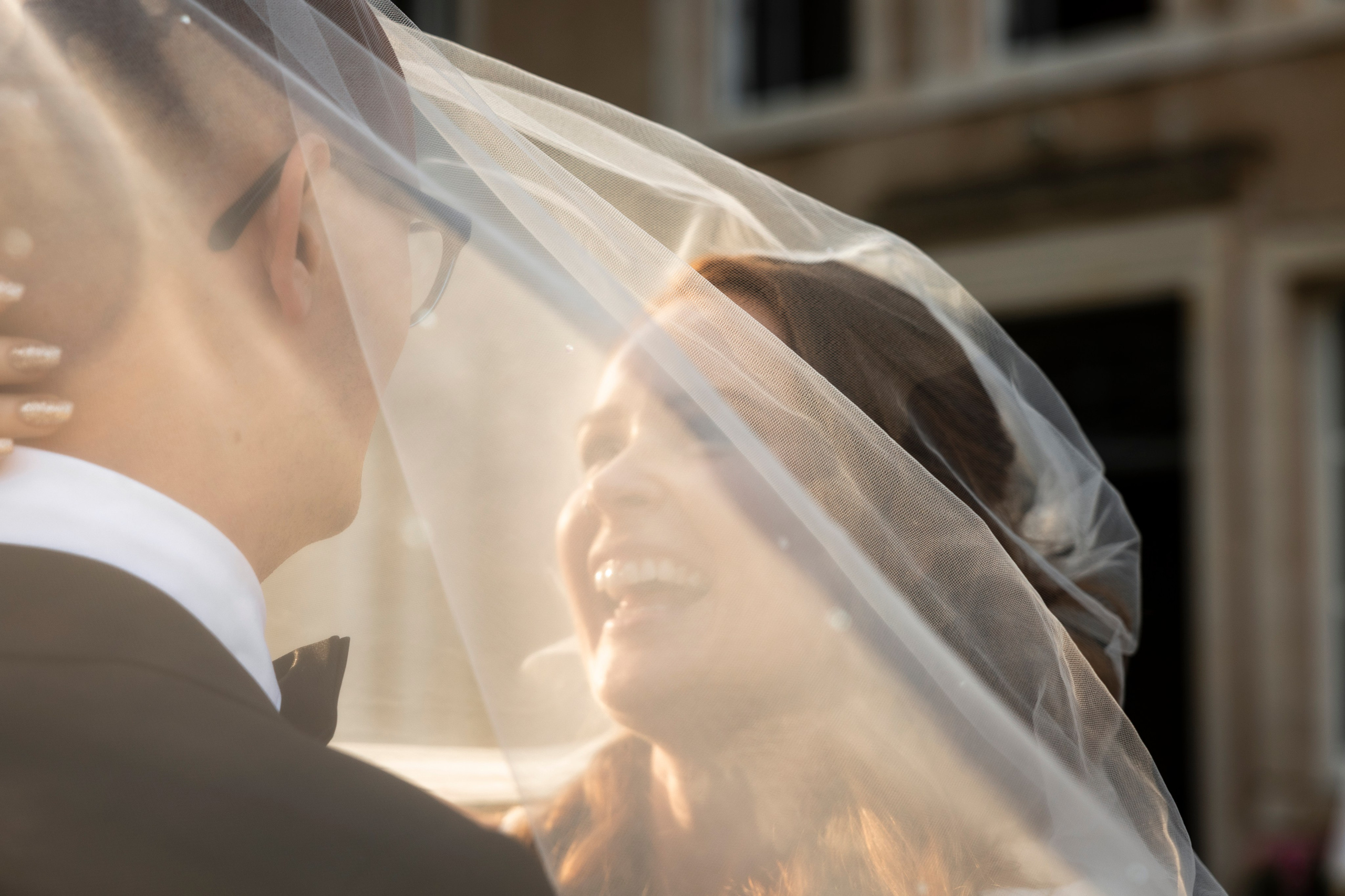 Bride and groom kissing beneath her cathedral veil